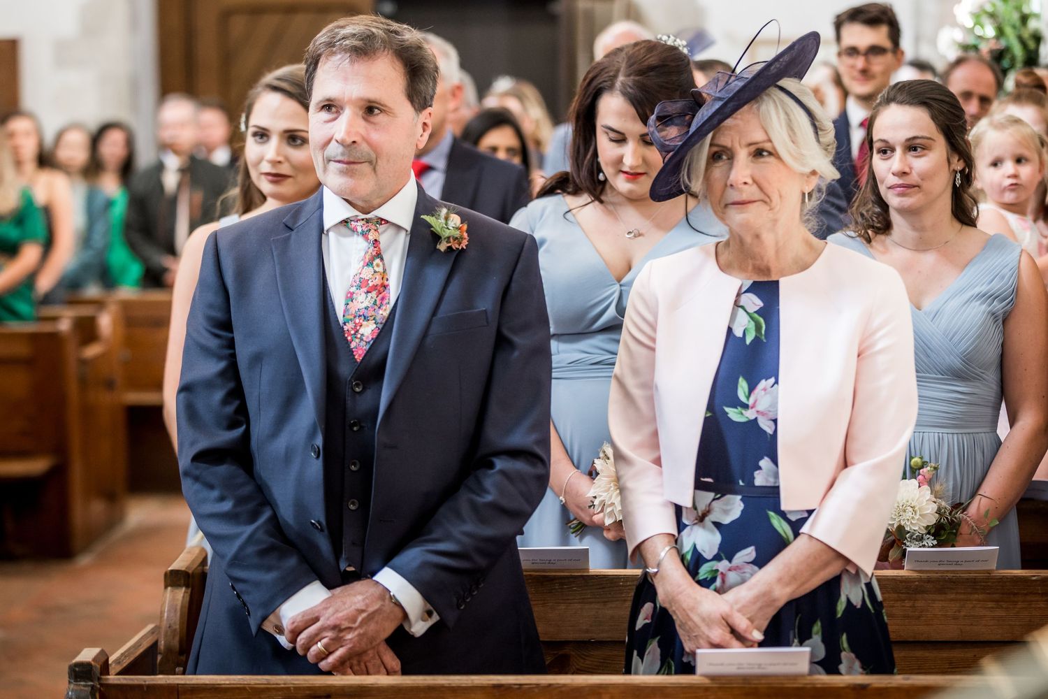 Wedding attendees seated in church pews during an emotional ceremony moment.