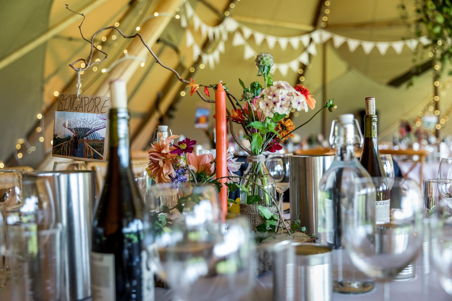 Wedding reception table decor with hanging lights and floral arrangements.