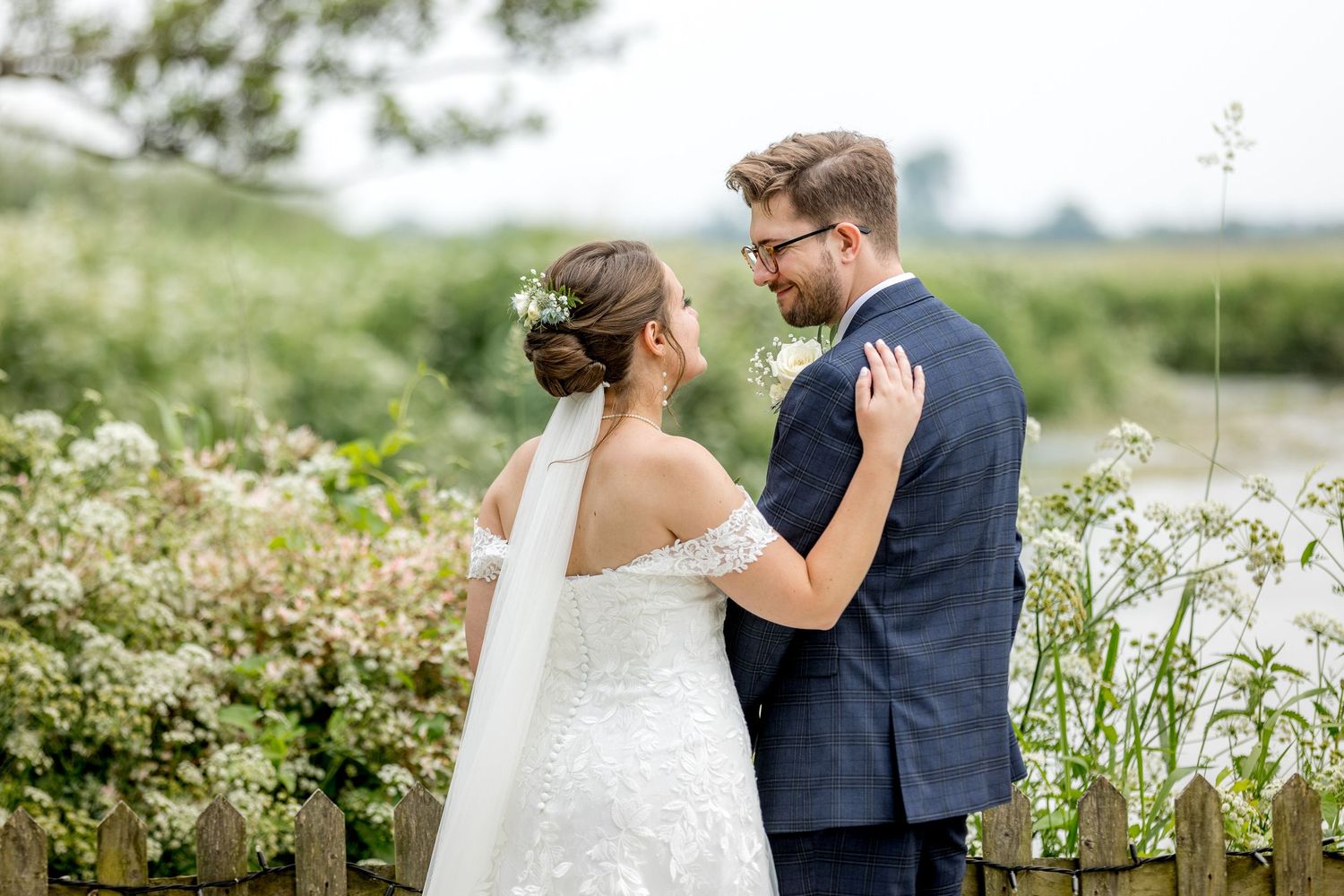 A romantic wedding portrait amidst blooming white flowers in a garden setting.