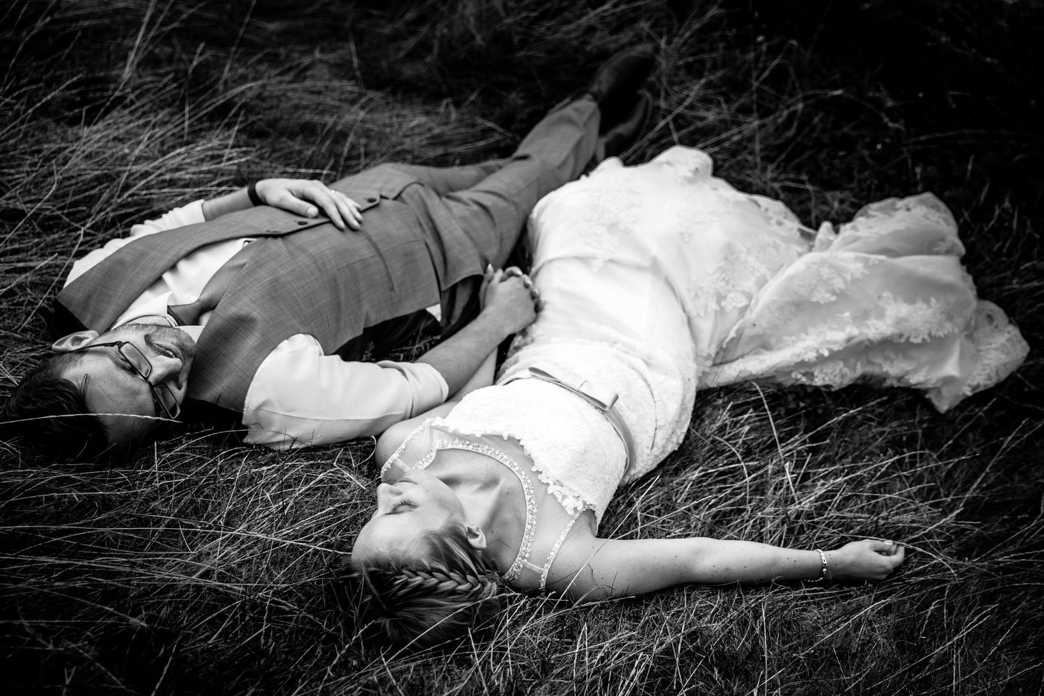 Artistic black and white photo of wedding dress spread out on grass.