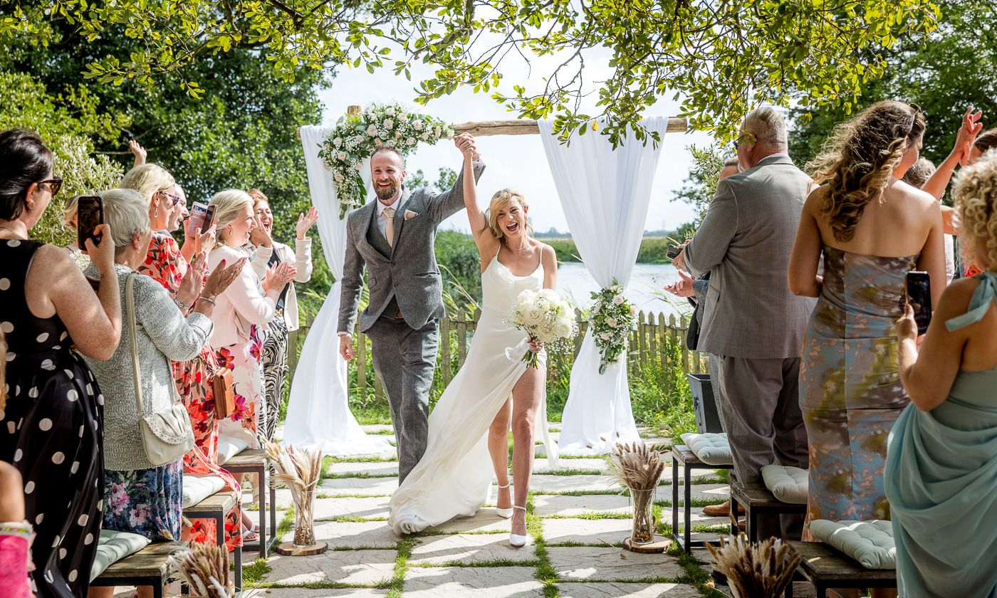 Outdoor wedding ceremony setup with white chairs and floral decorations by the water.