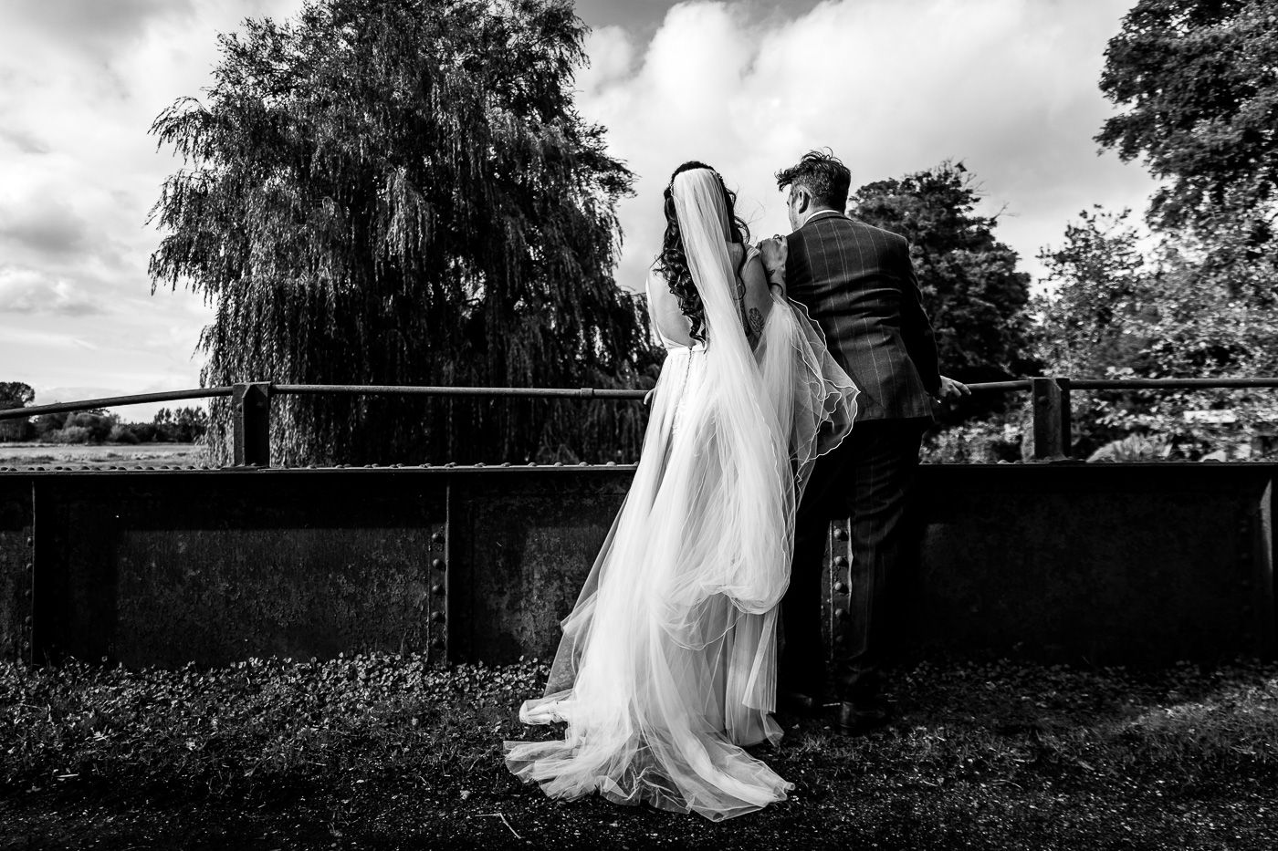 Black and white wedding portraits captured in dramatic outdoor setting with trees.