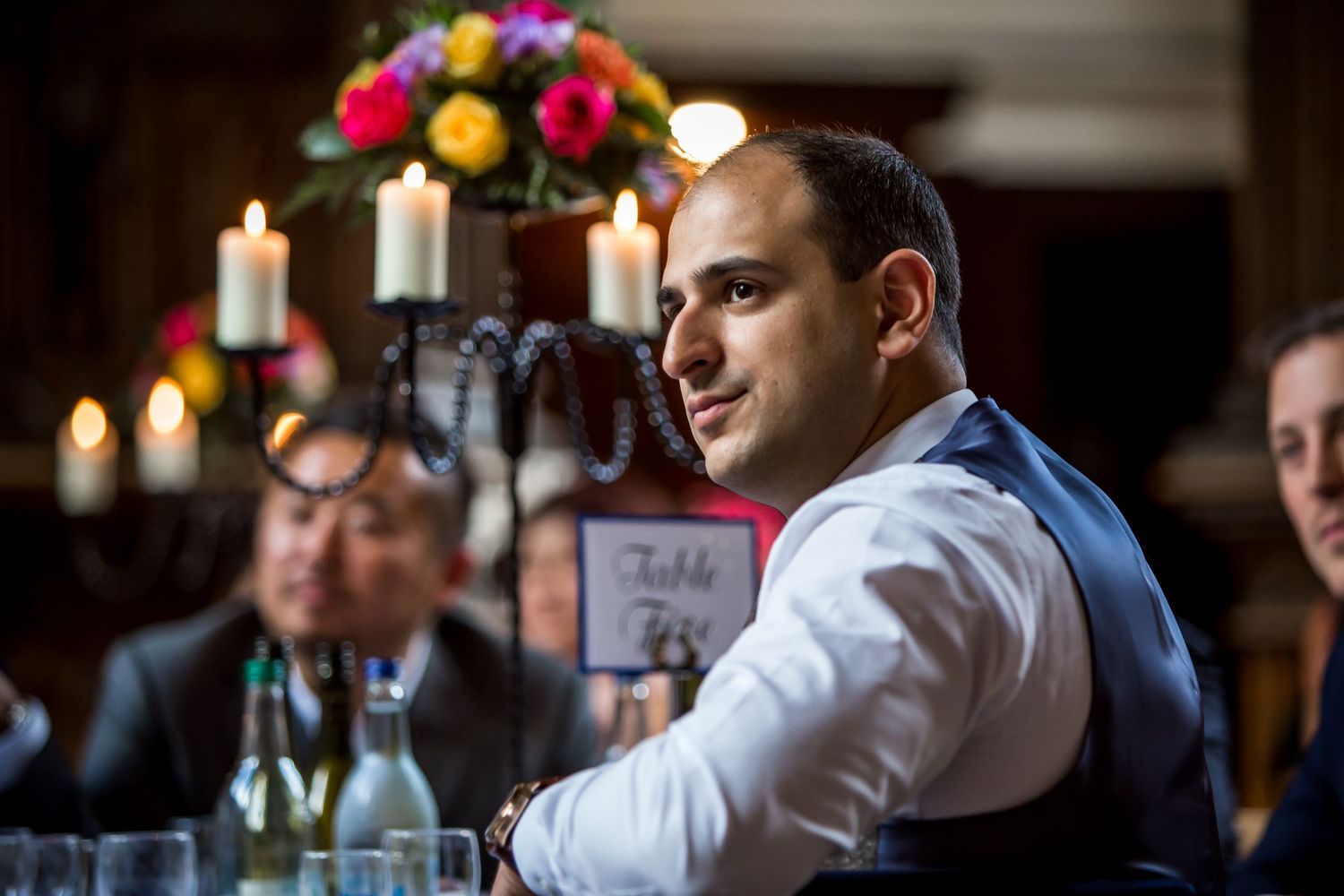 Photograph of a wedding guest watching the speeches in the dining room at Milton Abbey School, Dorset wedding venue