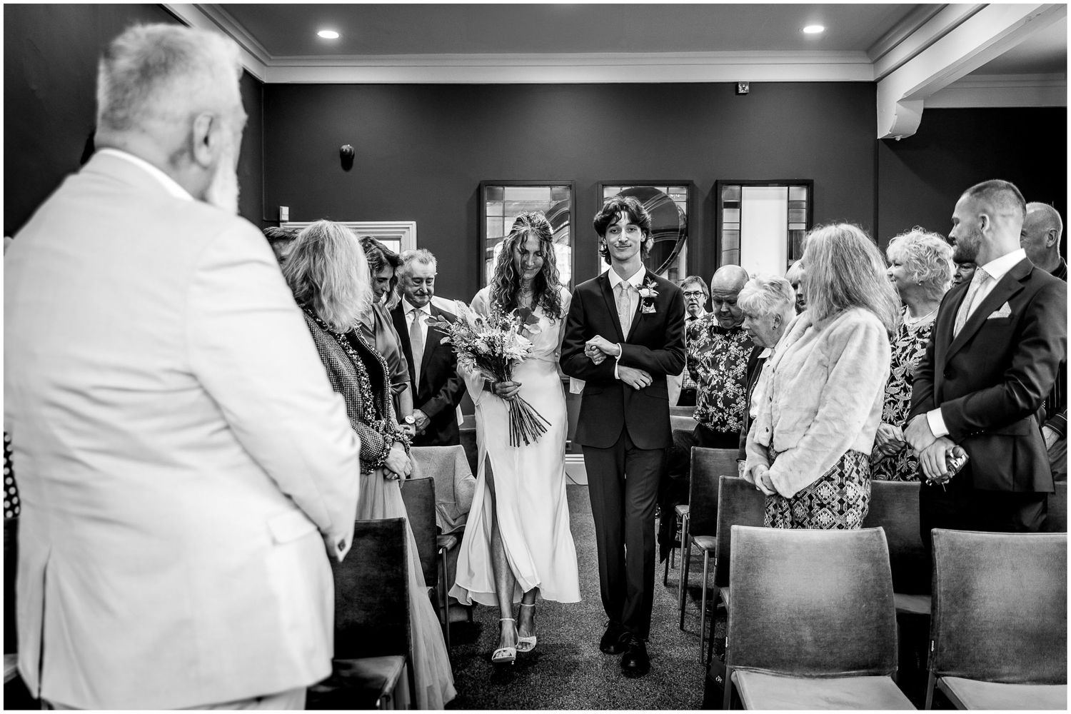 The bride walks down the aisle in Winchester's Castle room to meet her groom.