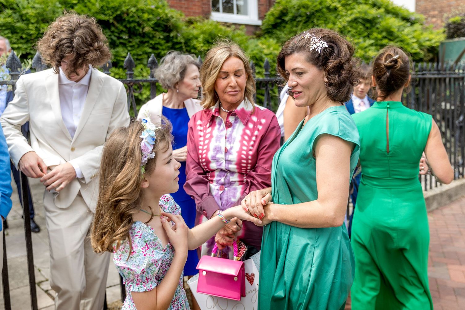 Wedding party guests in colorful dresses celebrate joyfully outdoors at a garden reception.