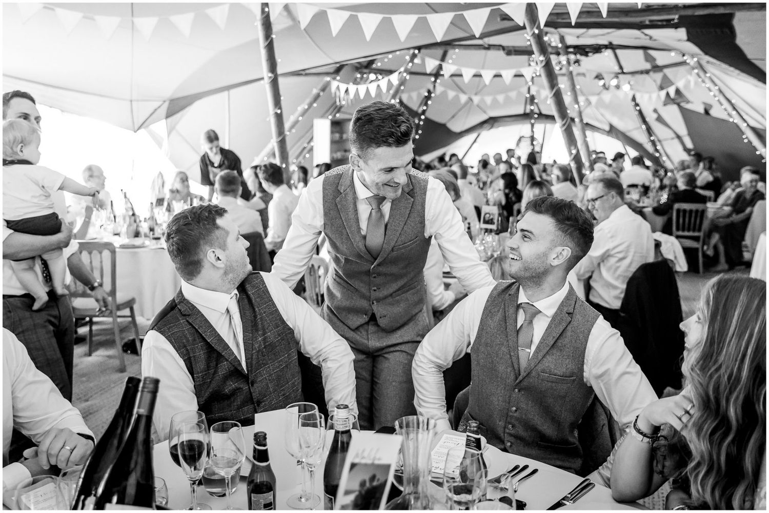 Wedding guests socializing and celebrating during the reception in black and white.