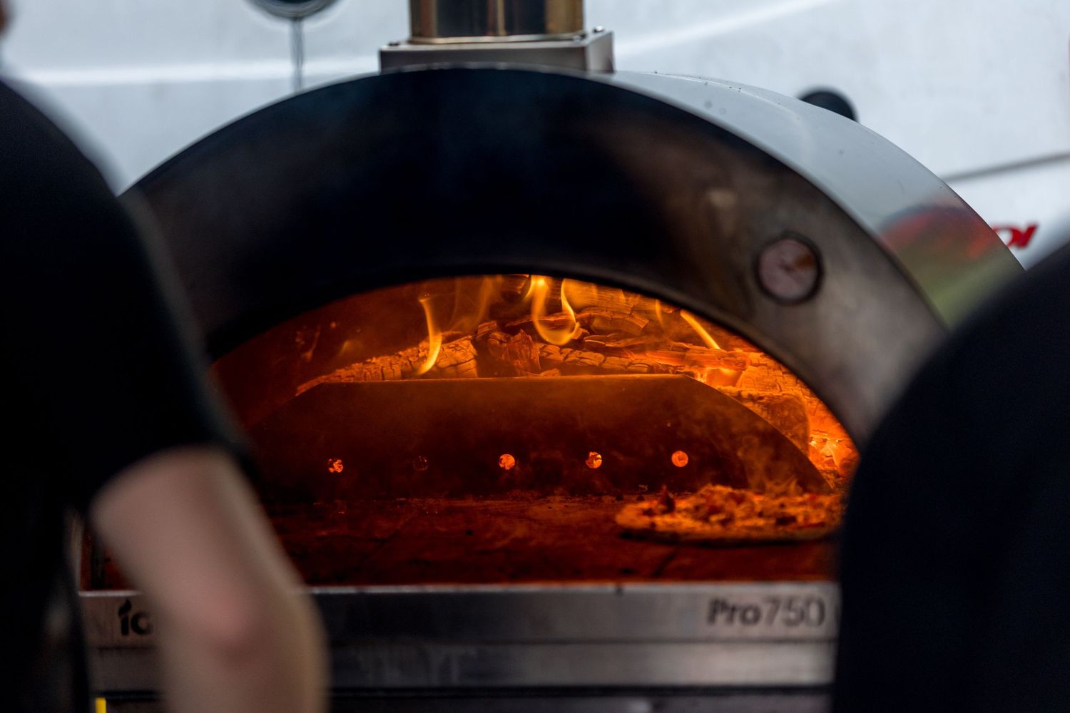 Close-up view of glowing wood-fired pizza oven flames.