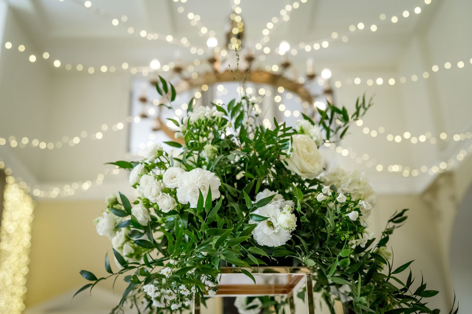 String lights and lush floral centerpieces decorate an elegant wedding reception space.