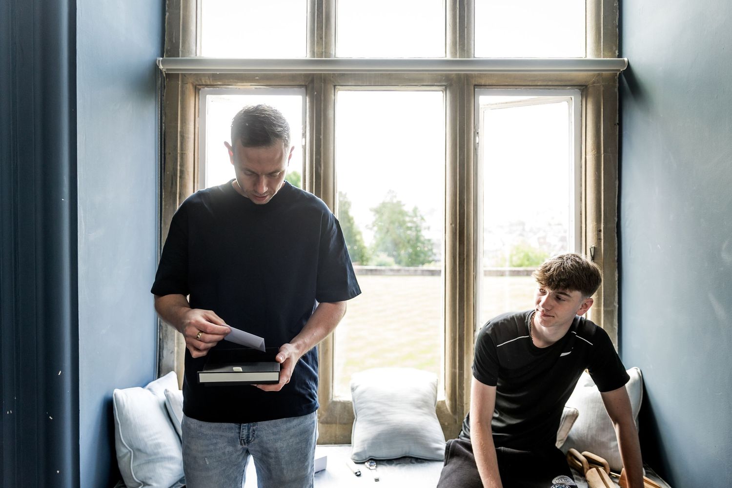 Two people reviewing documents together by large windows in modern room.