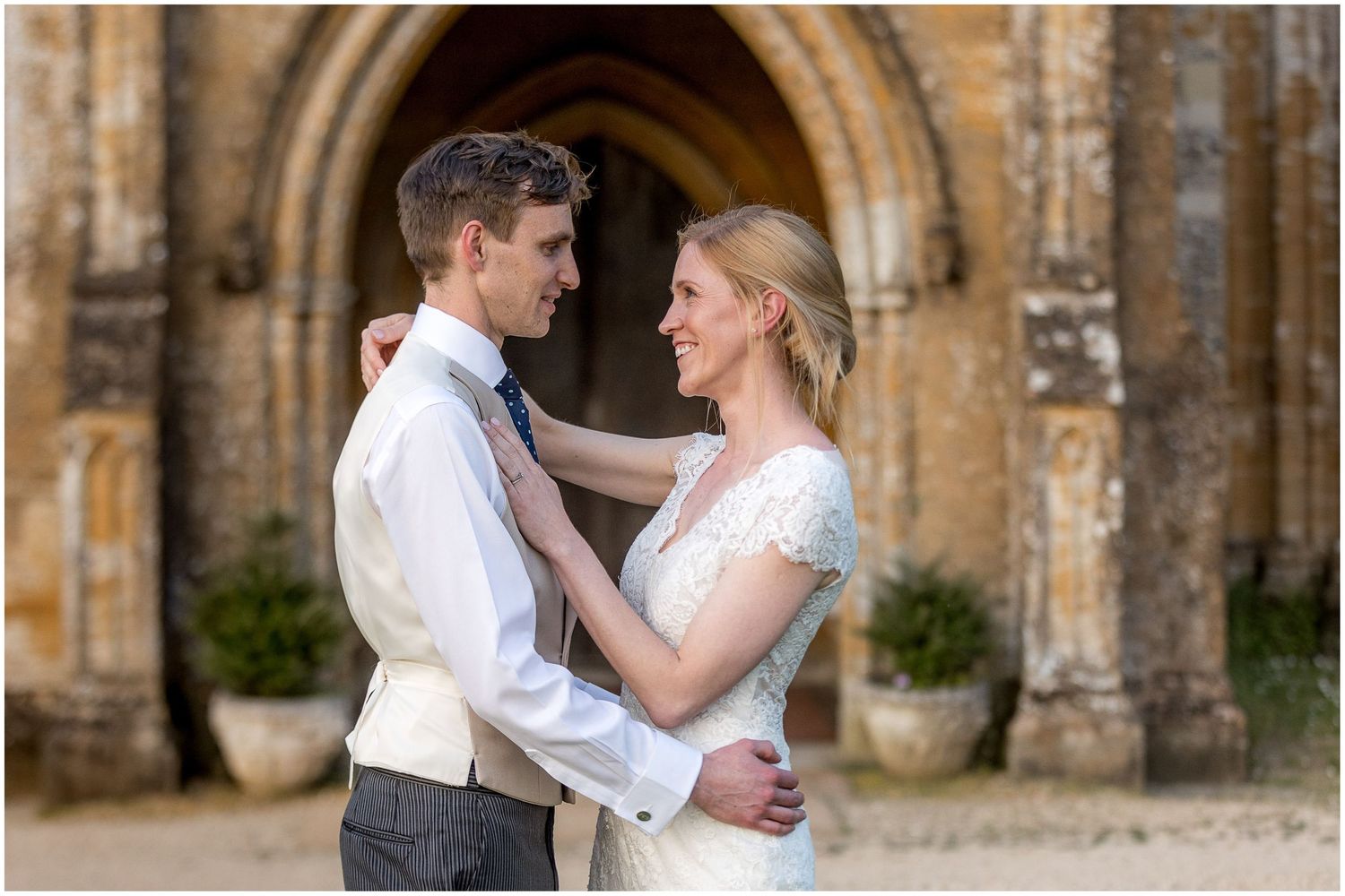 Romantic couple embracing in front of historic stone archway.