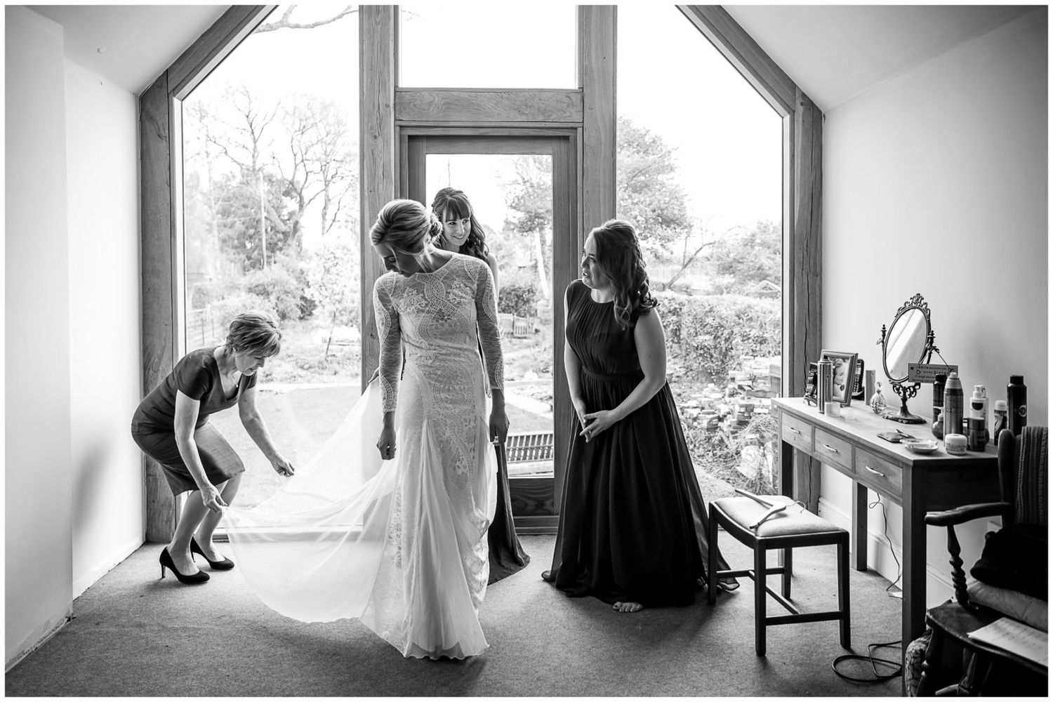 Black and white panoramic series showing wedding day preparations by large windows.