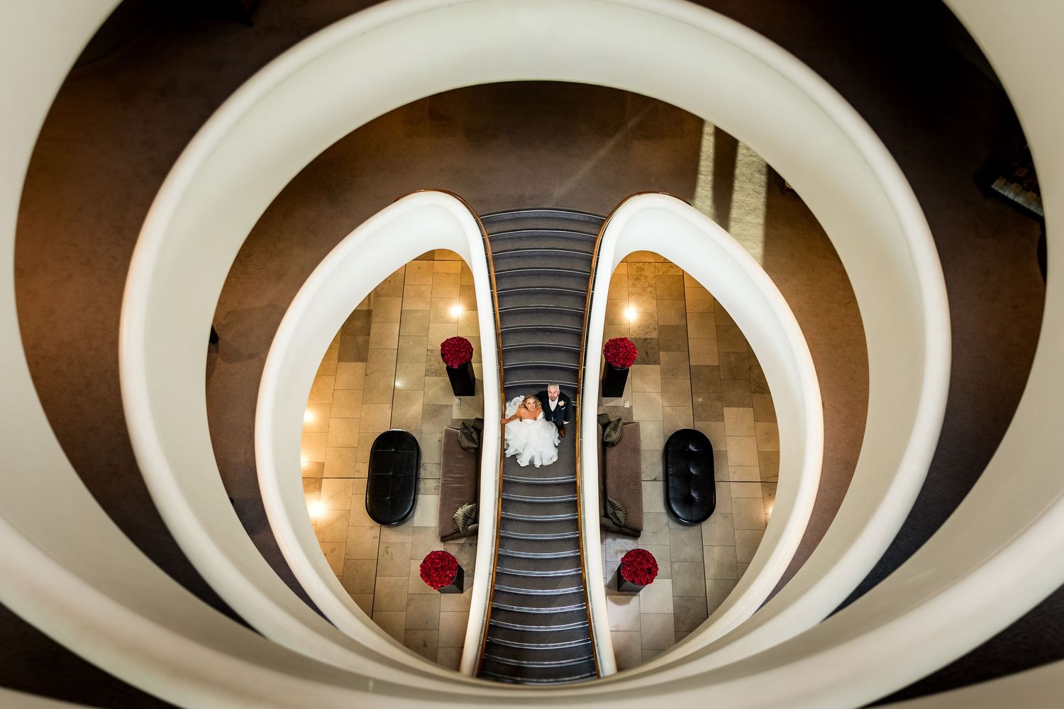 Aerial view of a stunning spiral staircase with elegant curves, featuring a couple in the center below.