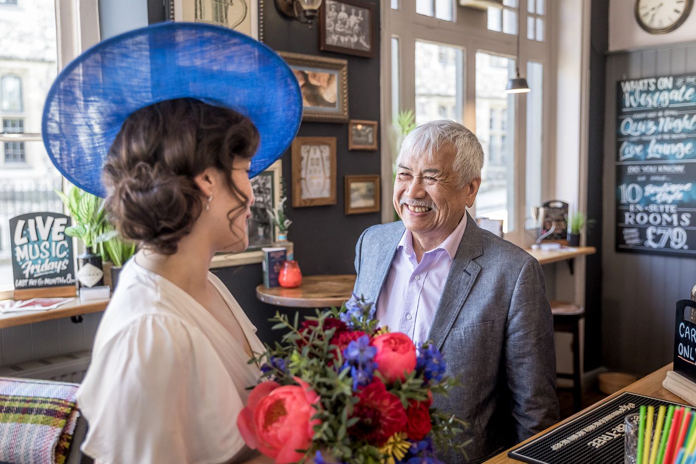 A charming moment at a pub wedding reception with bright pink flowers on the table.