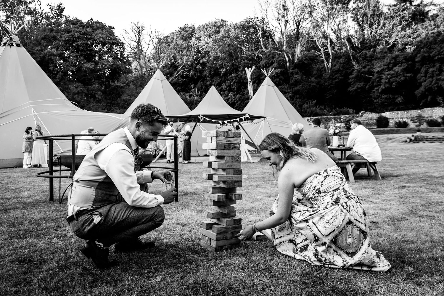 Black and white panorama of guests relaxing on blankets at an outdoor gathering.