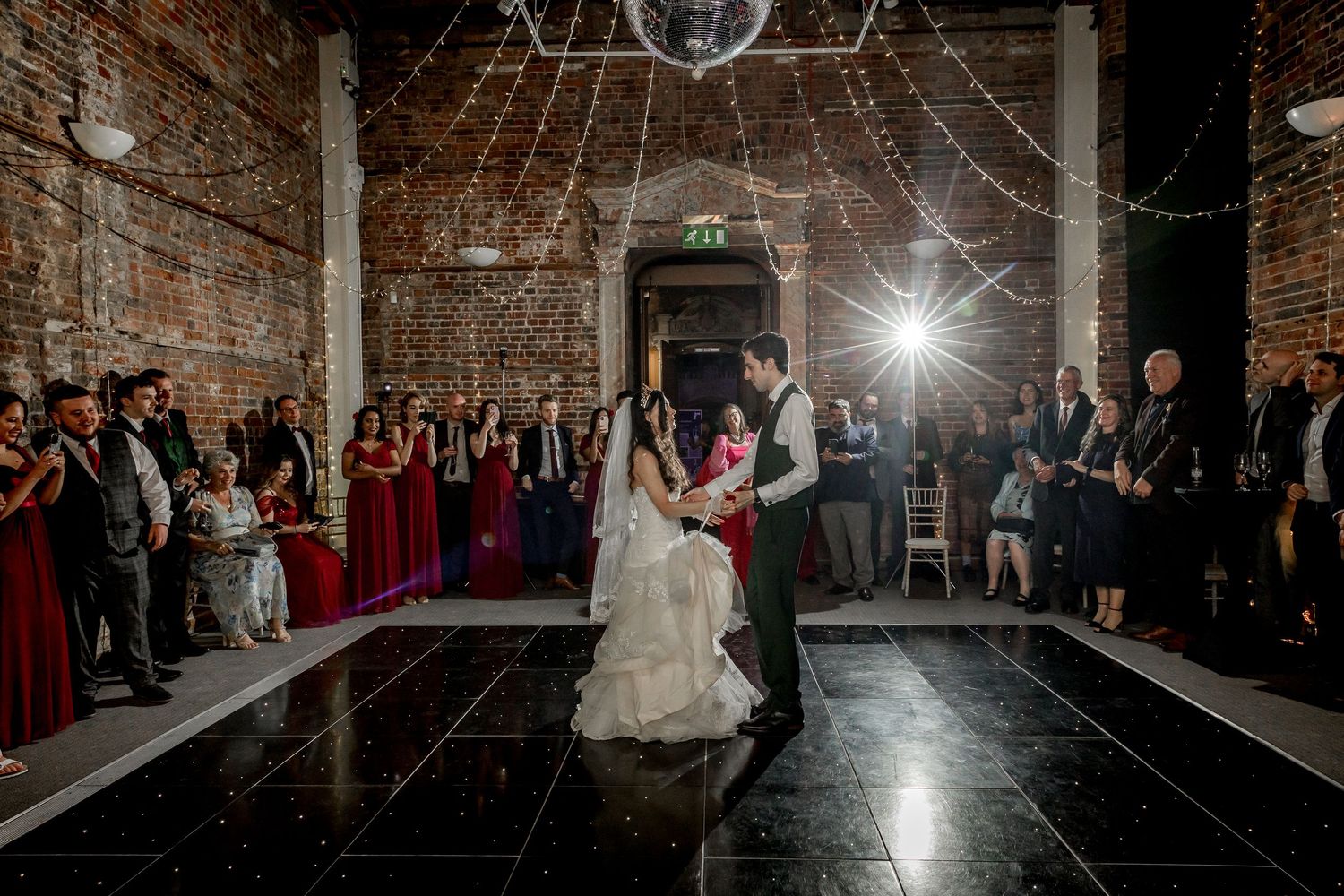 Wedding reception dance floor with disco ball in rustic brick venue.