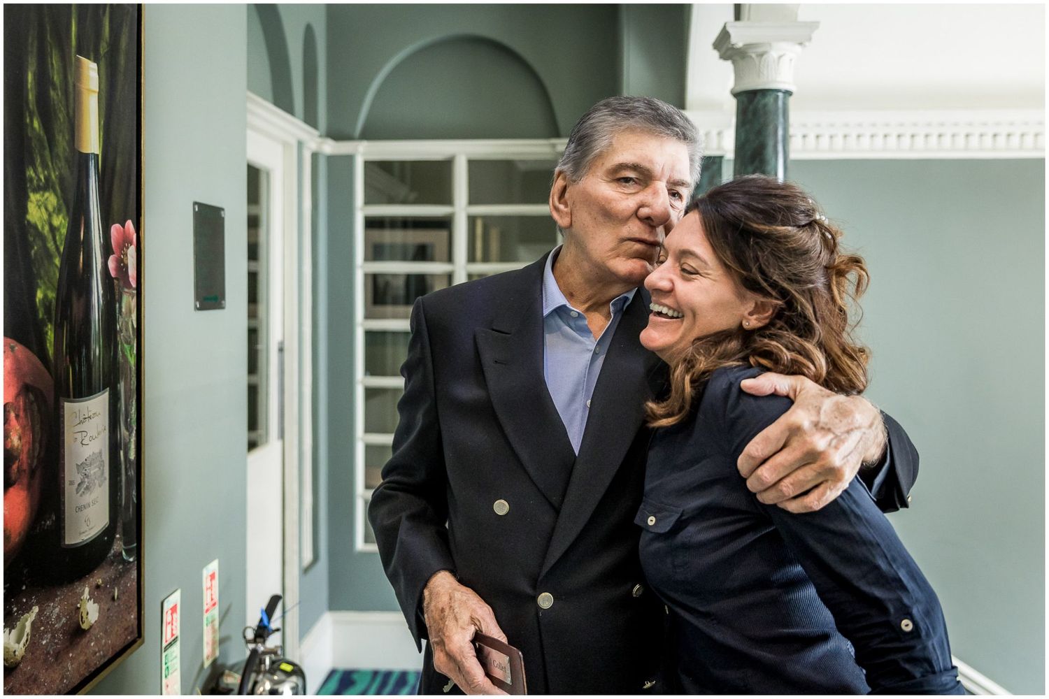Emotional candid moment shared in an elegant interior with mint green walls.