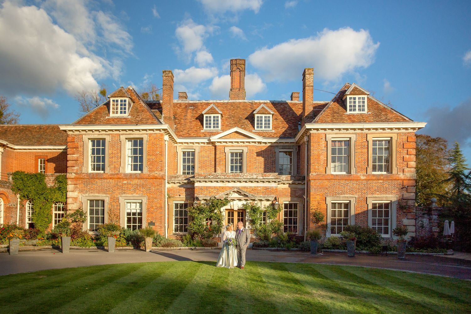 A grand Georgian mansion with symmetrical windows and dormer windows under bright blue skies.