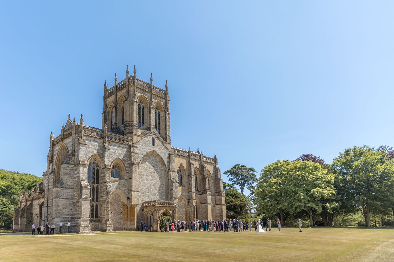 Exterior view of a grand Gothic church with manicured lawns on a sunny day.