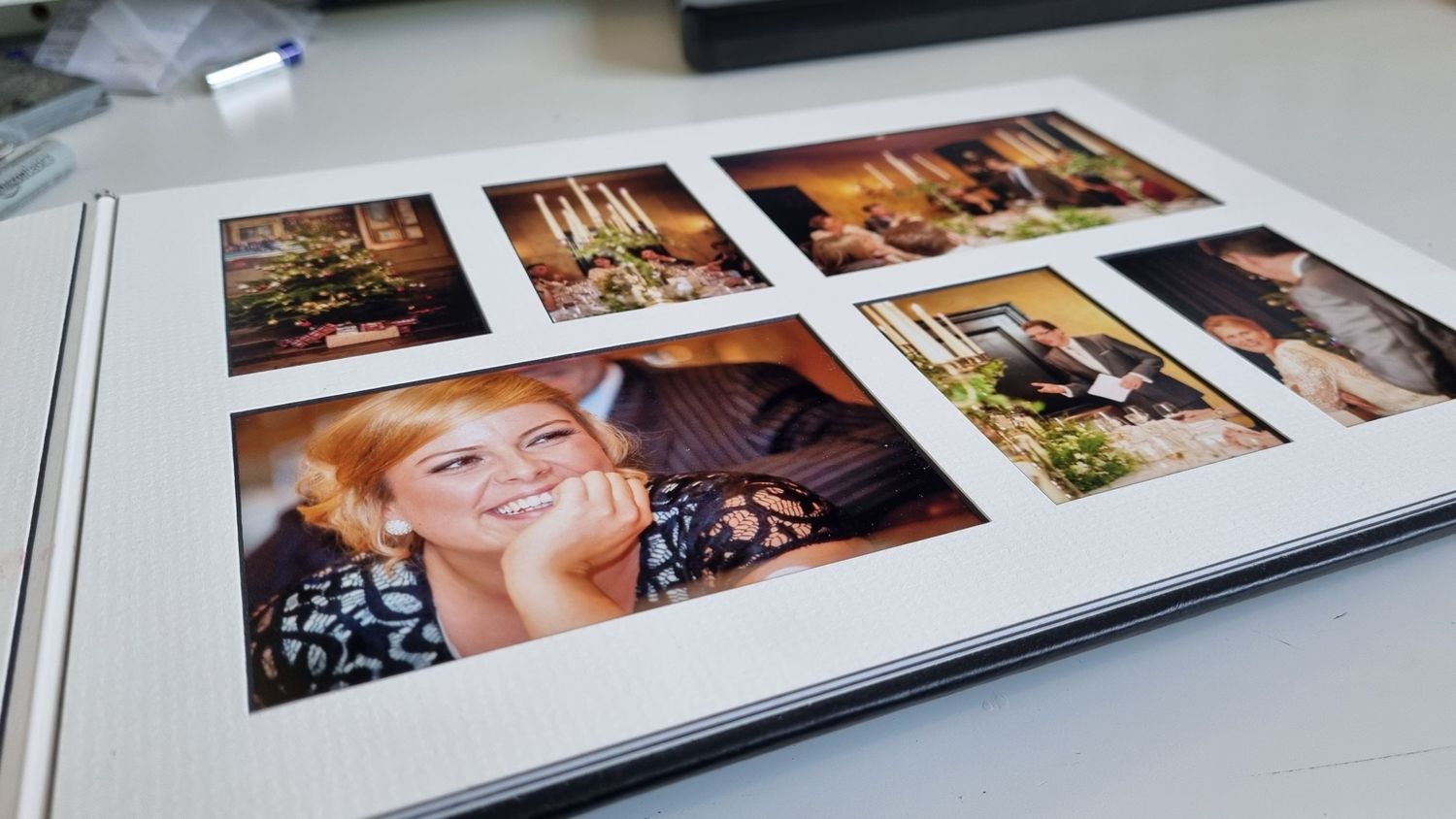 Multiple photo albums or wedding books laid out on a white surface showing various printed photographs and layouts.