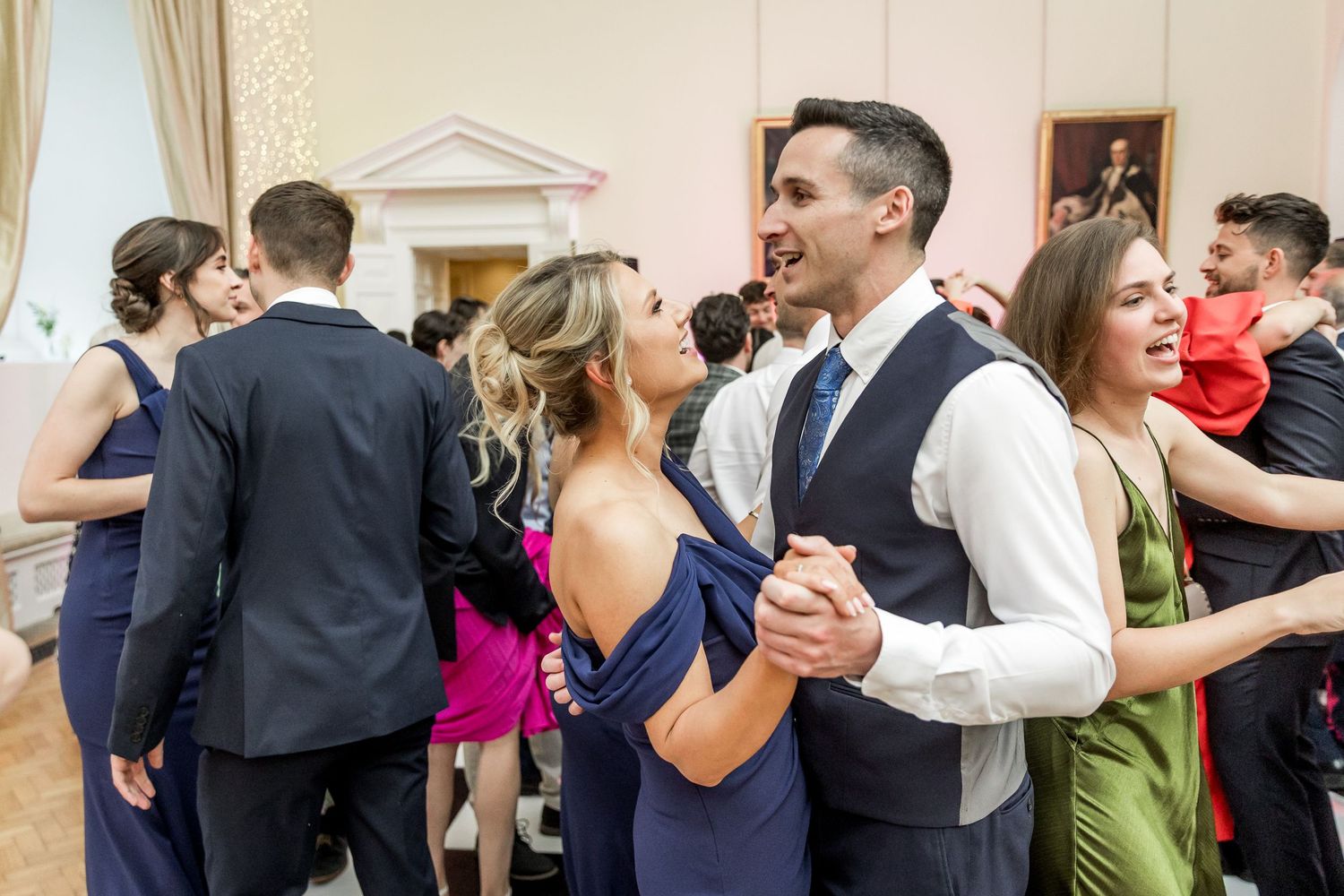 Couples dancing together during an elegant indoor wedding reception with formal attire.