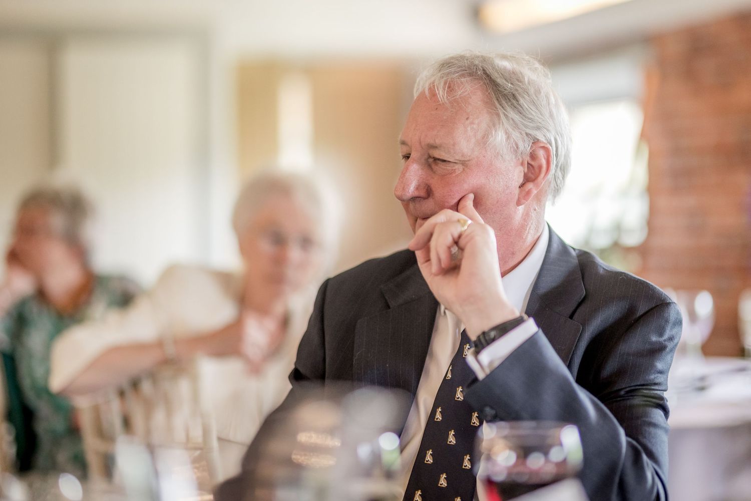Guests enjoying conversation at a wedding reception in an elegant brick-walled venue.