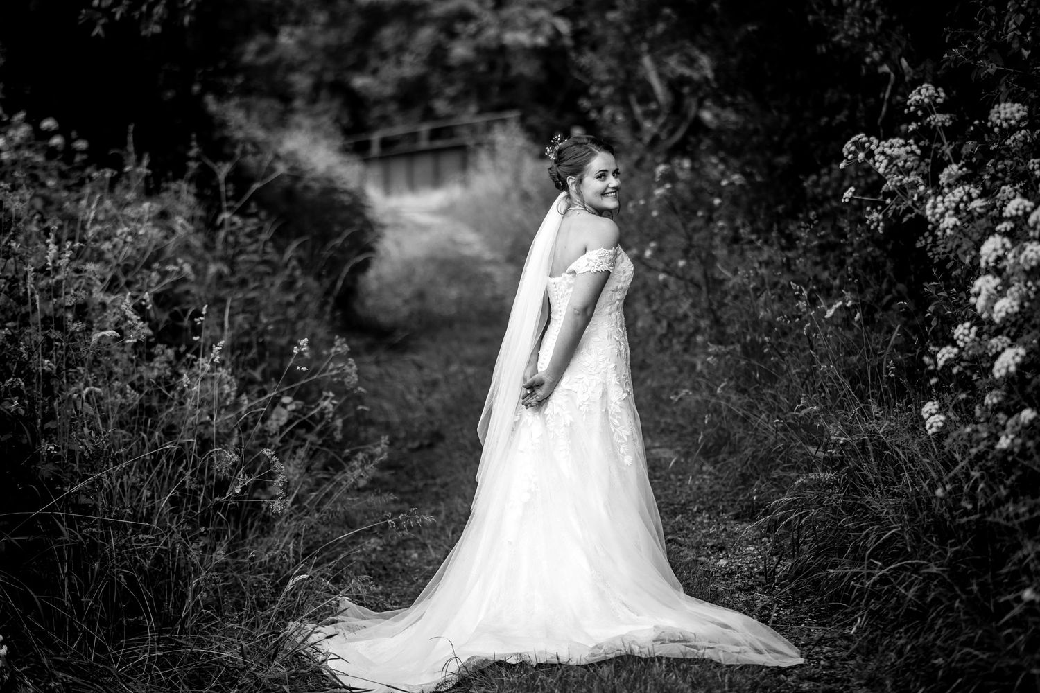 Black and white wedding portrait captured in a romantic garden landscape.