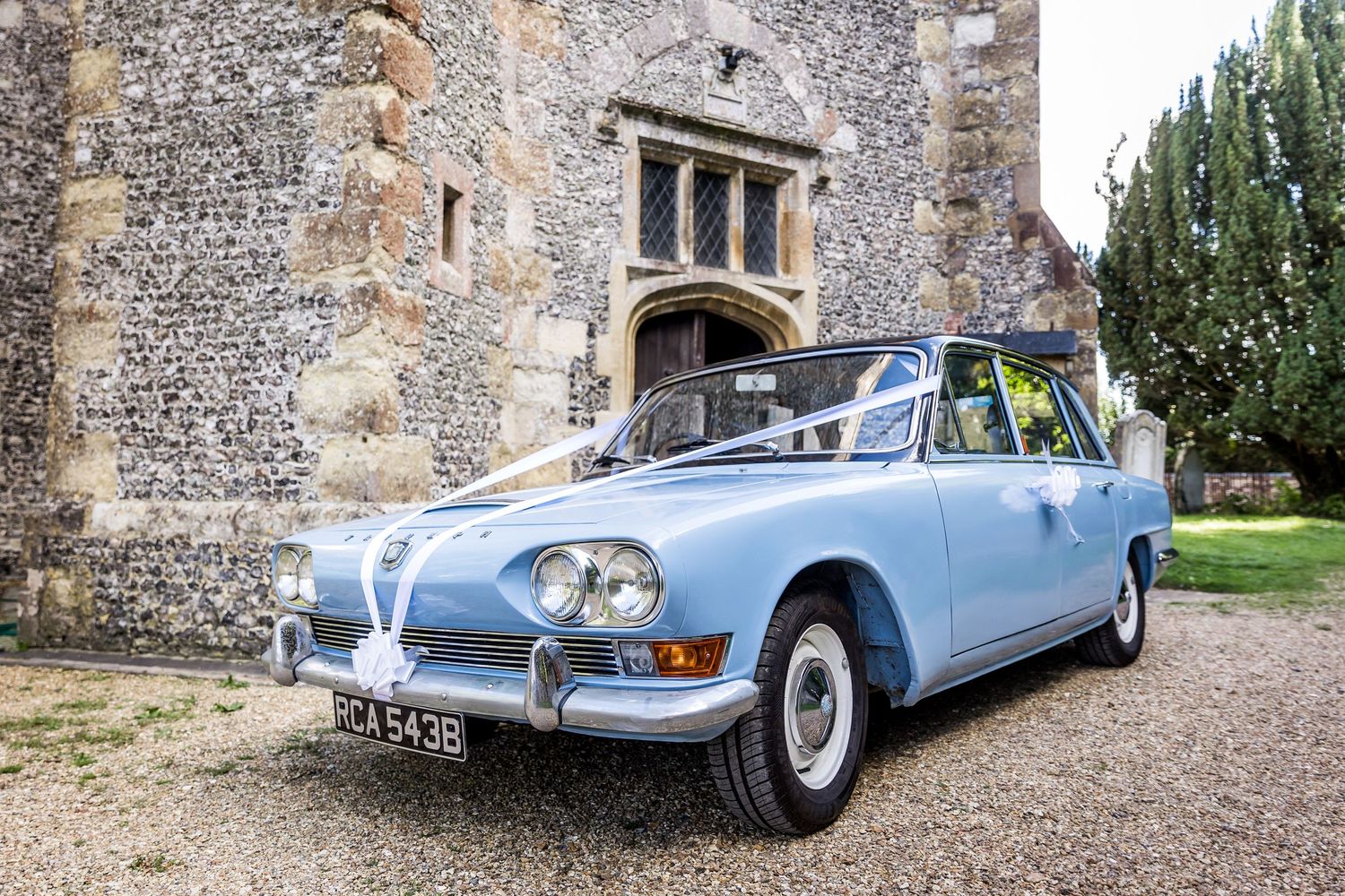 Vintage wedding cars parked outside a historic stone building.