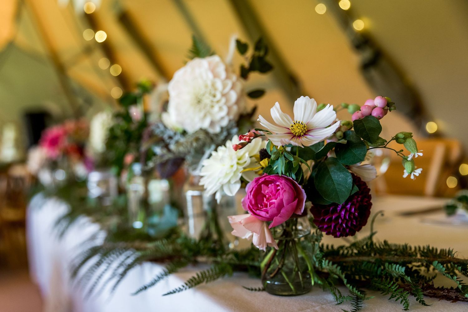 Close-up of romantic floral arrangements with pink and white blooms on reception tables.