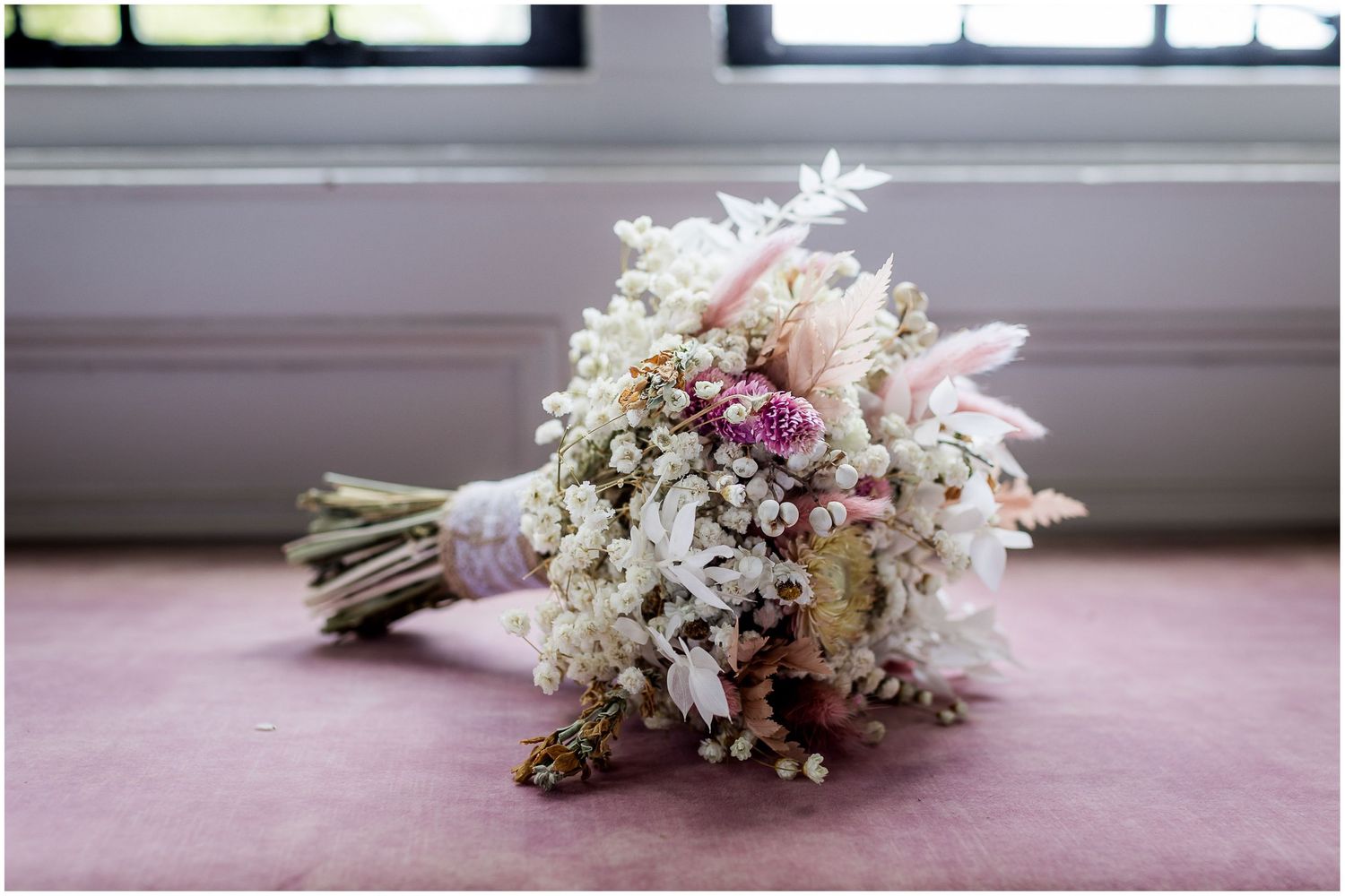 A white and pink bridal bouquet with delicate flowers sits on a pink surface in multiple angles.