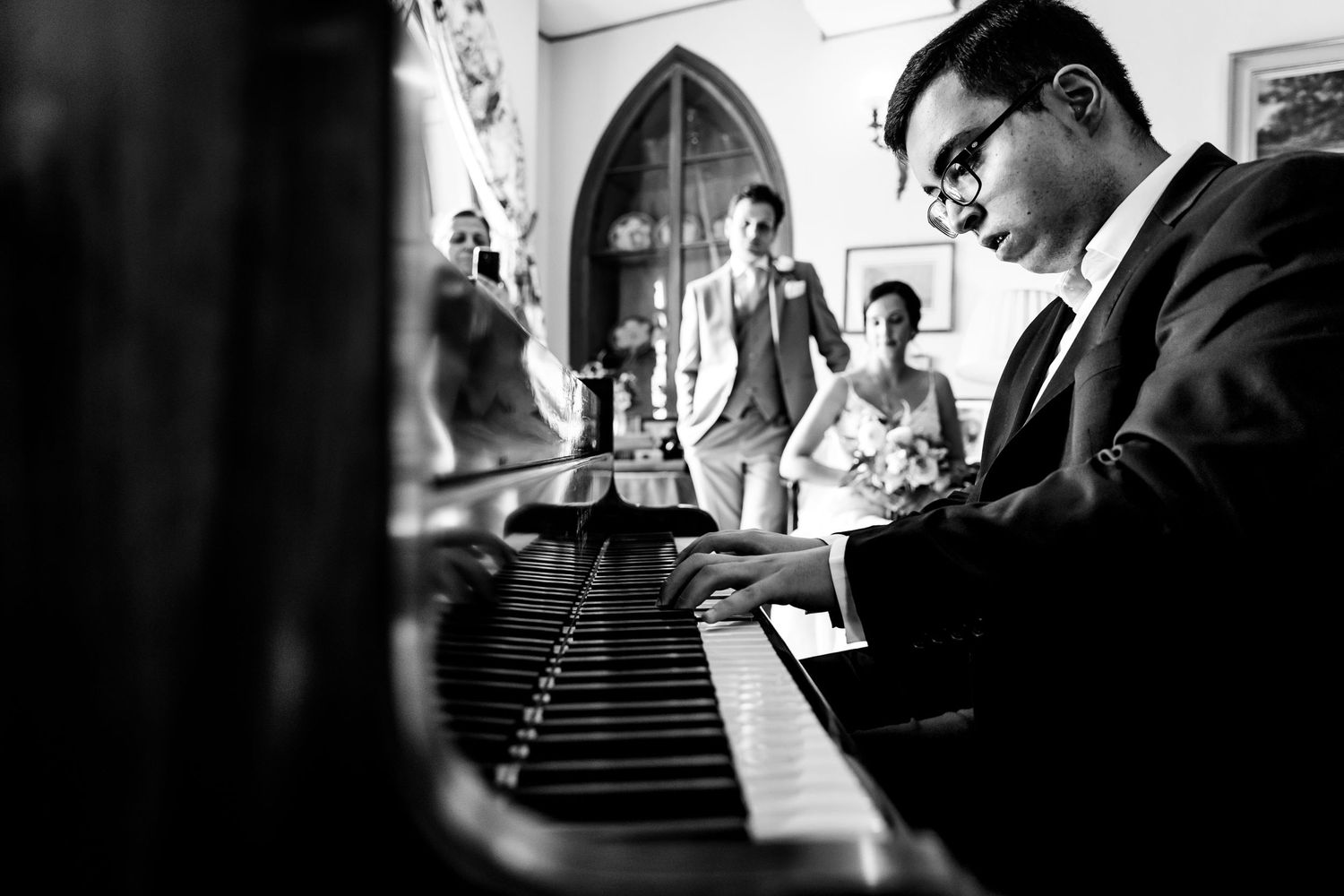 Dramatic black and white photograph capturing intimate moments at a piano.