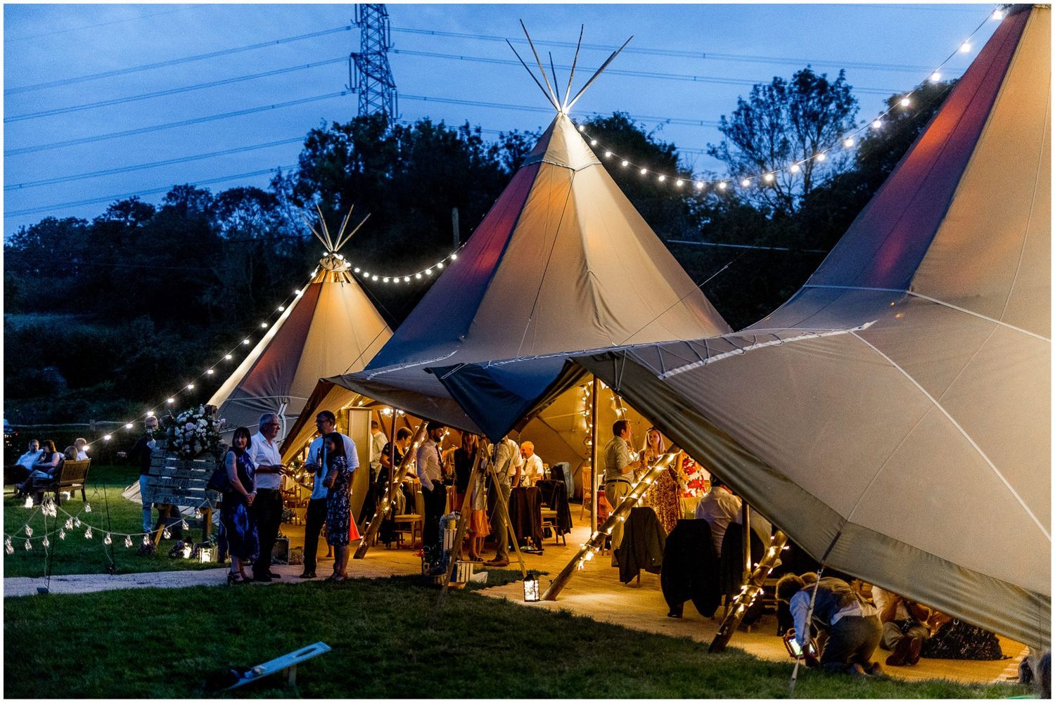 Tipi-style wedding venue at dusk with string lights creating magical atmosphere.