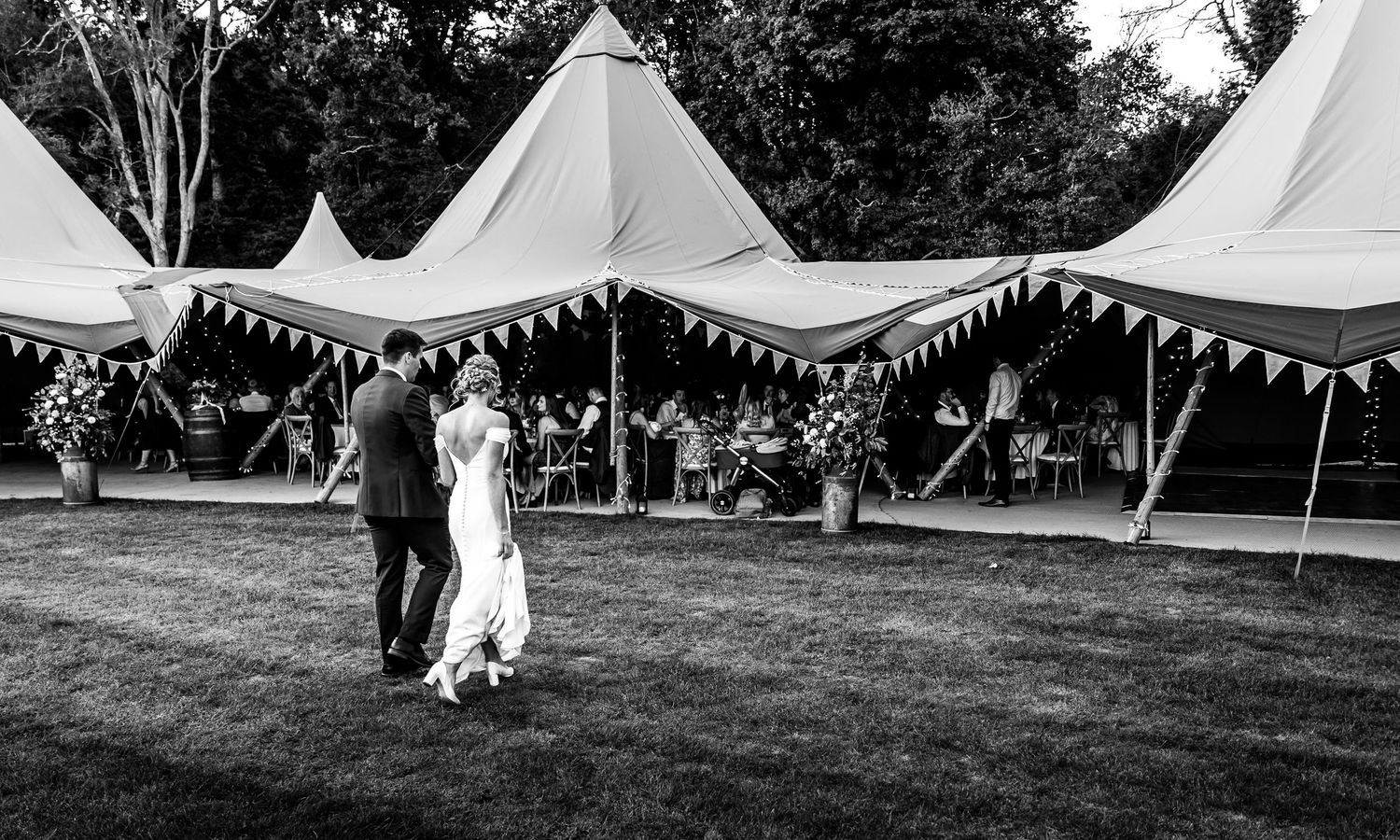 Large white wedding tents set up on grass field for outdoor reception.