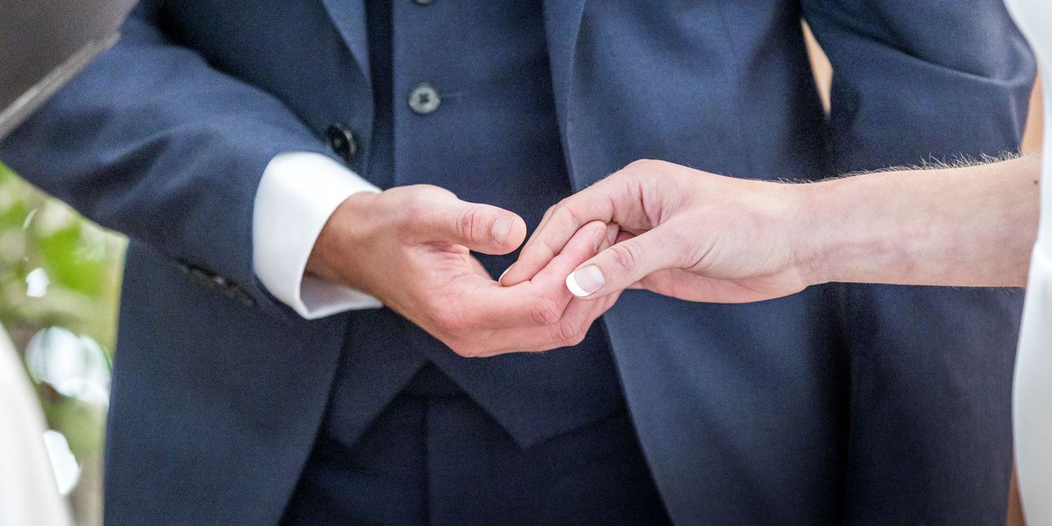 Close-up of hands exchanging rings during wedding ceremony.