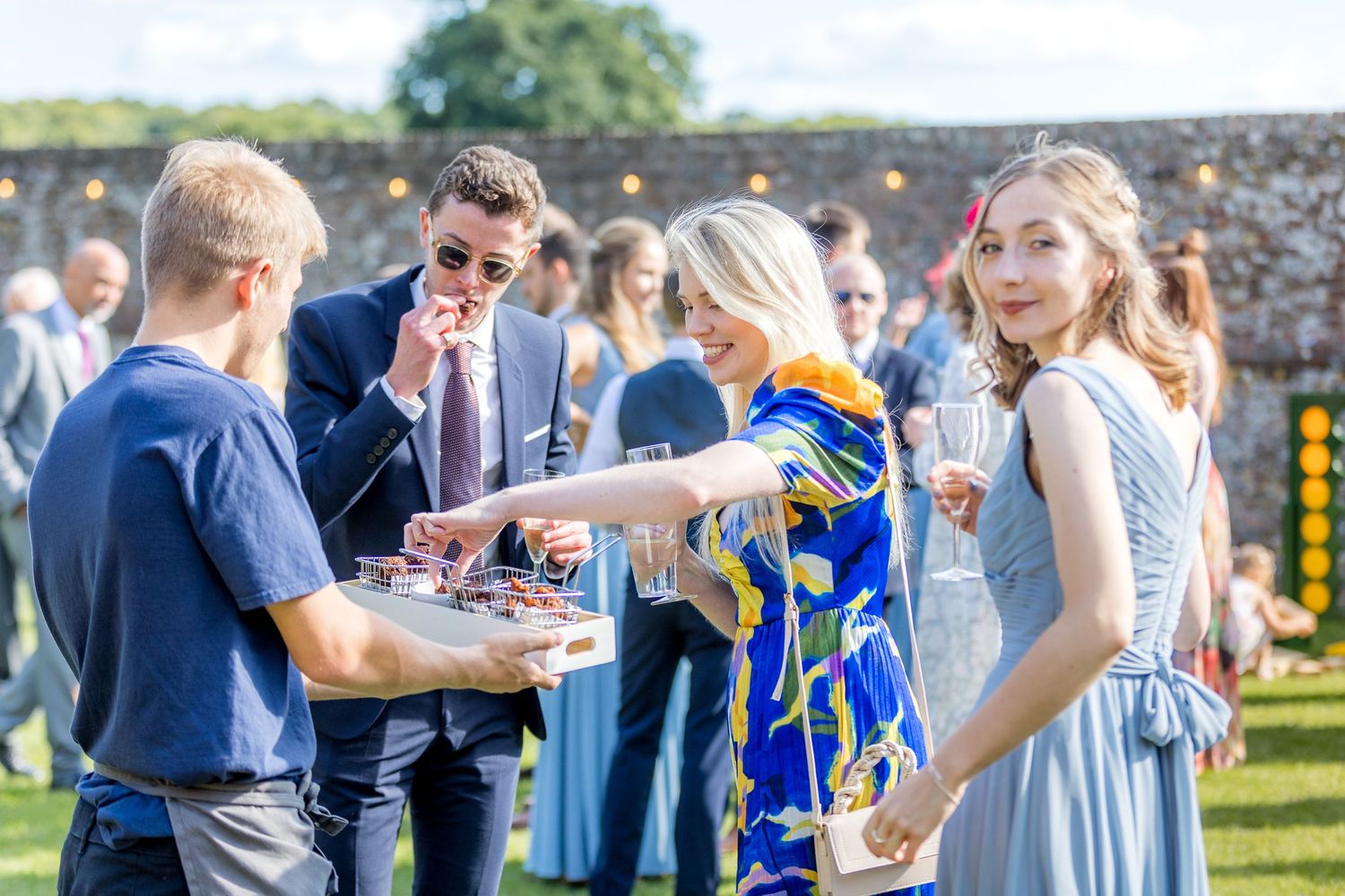Guests enjoy drinks and conversation at an elegant outdoor garden party.