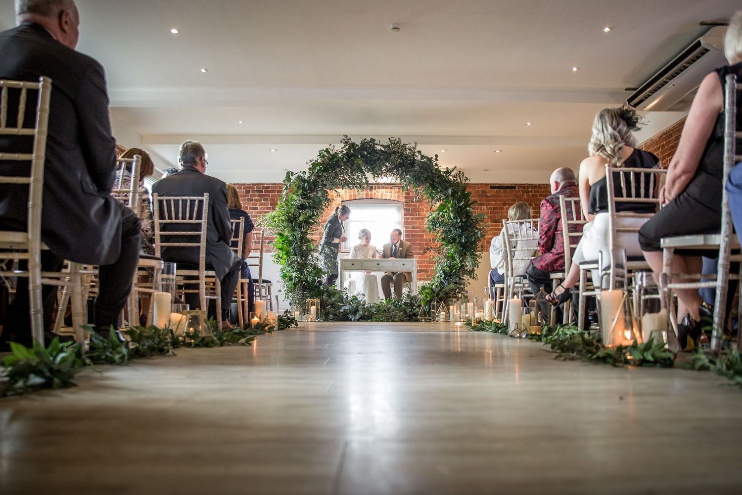 Long view of an elegant wedding reception venue setup with white decor and chairs.