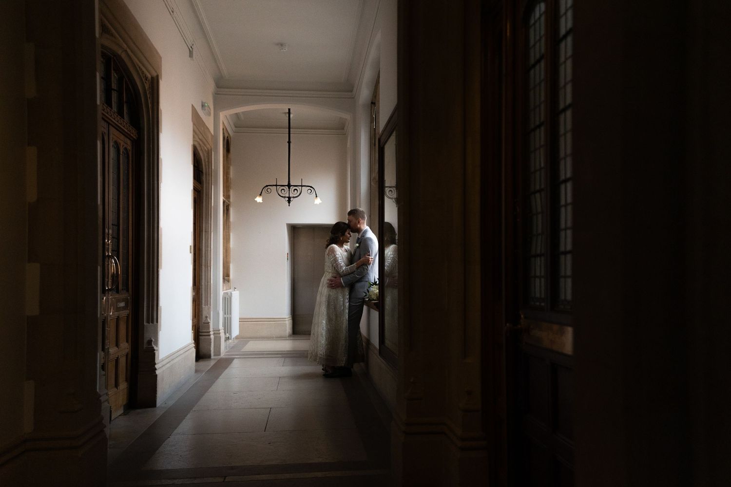 A silhouetted figure stands in a bright corridor of a historic building.