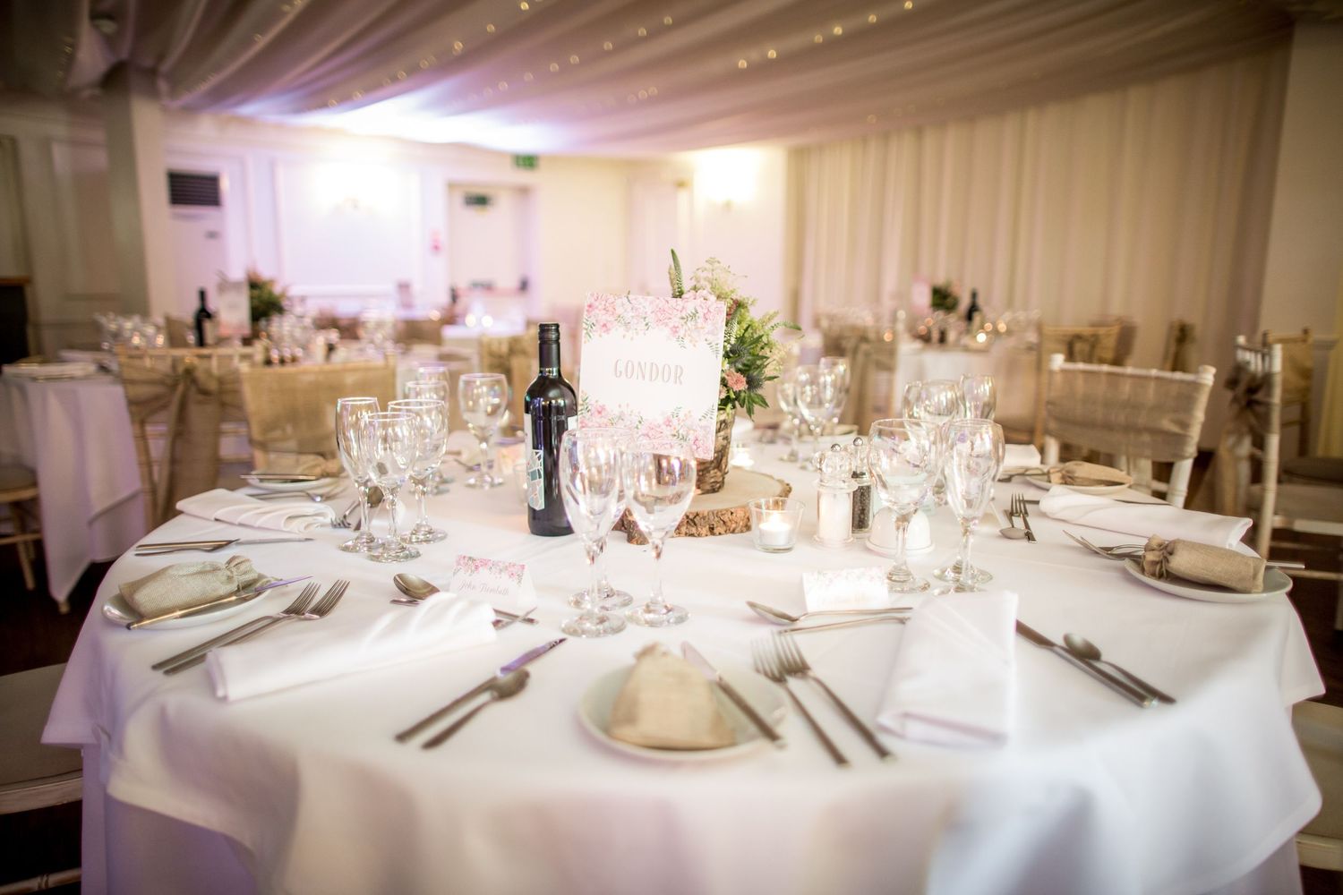 Elegant wedding reception table setting with white linens and centerpieces.