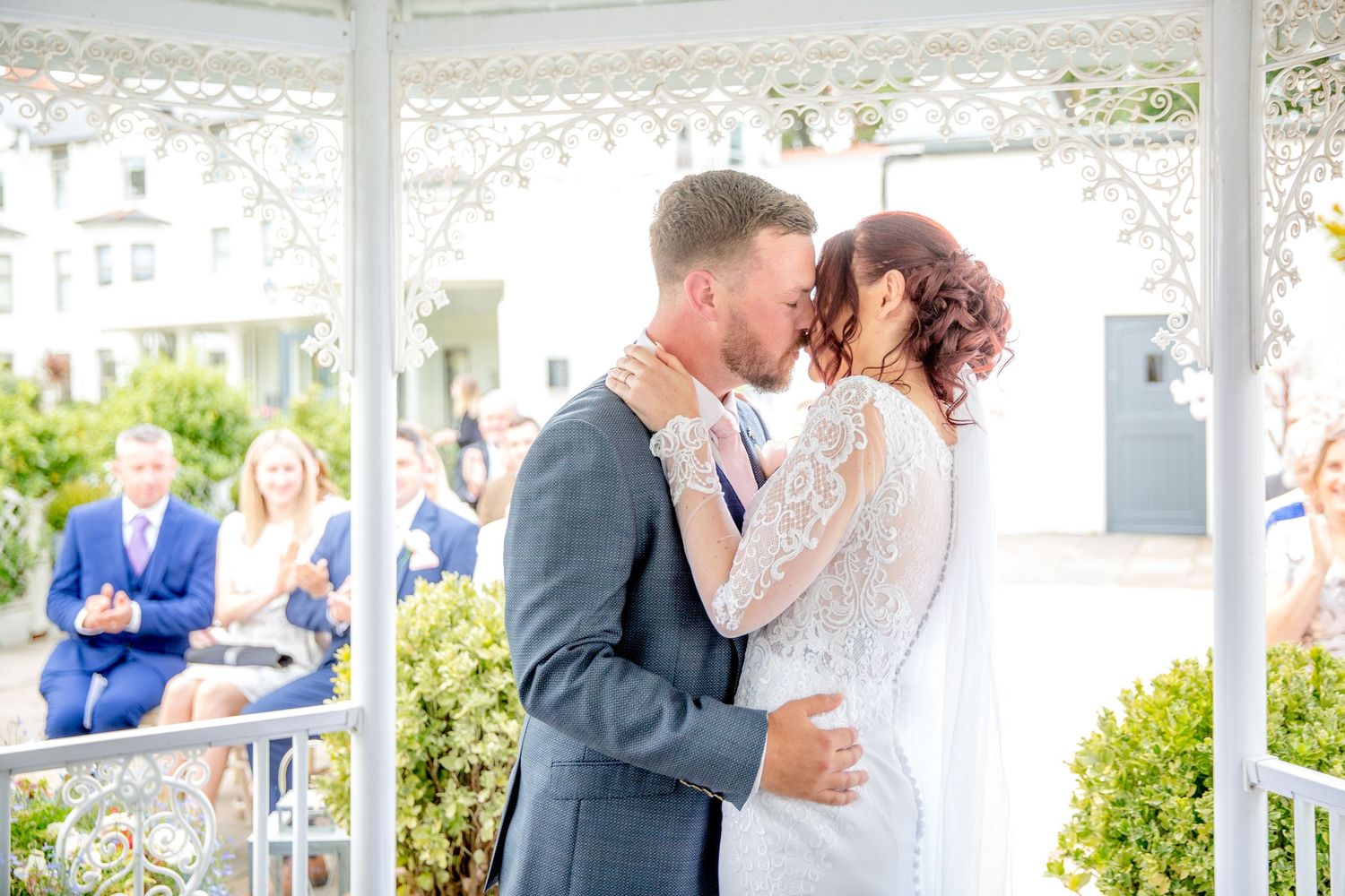 Wedding celebration under a white gazebo with guests in attendance.