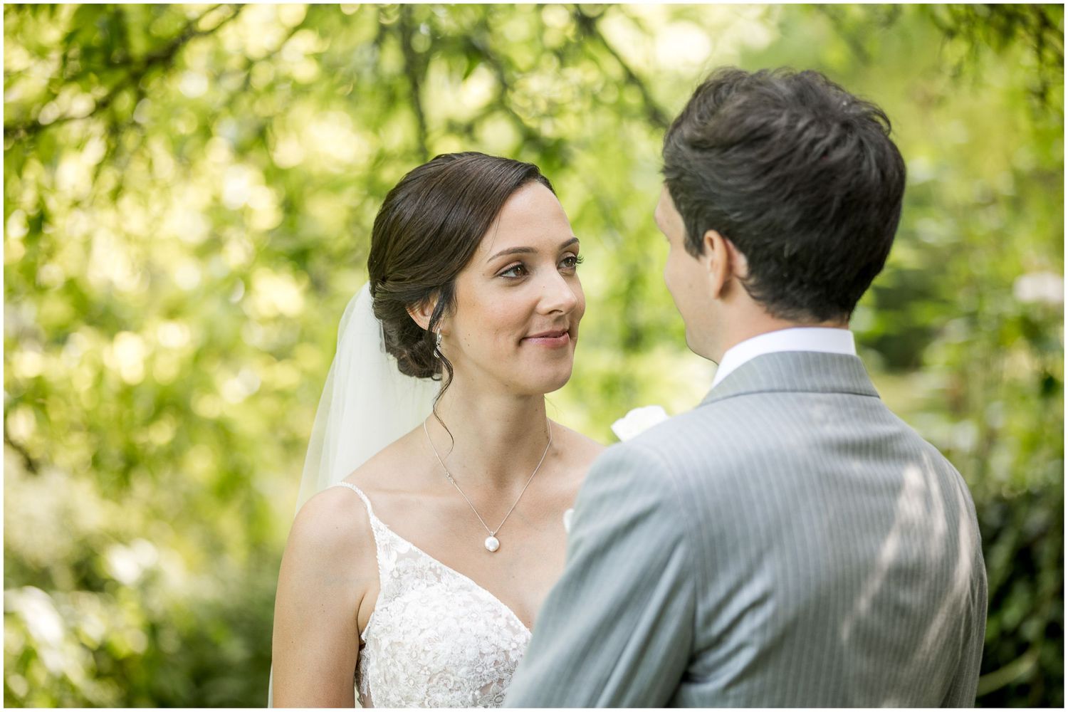 Romantic outdoor wedding portraits under green leafy trees in natural lighting.