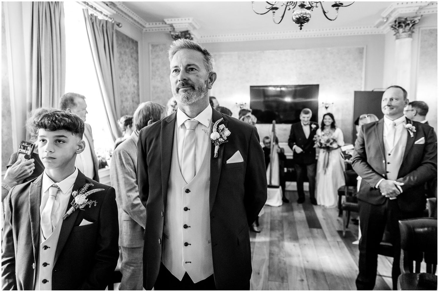 Wedding ceremony guests and wedding party members share joyful moments in an elegant indoor venue.