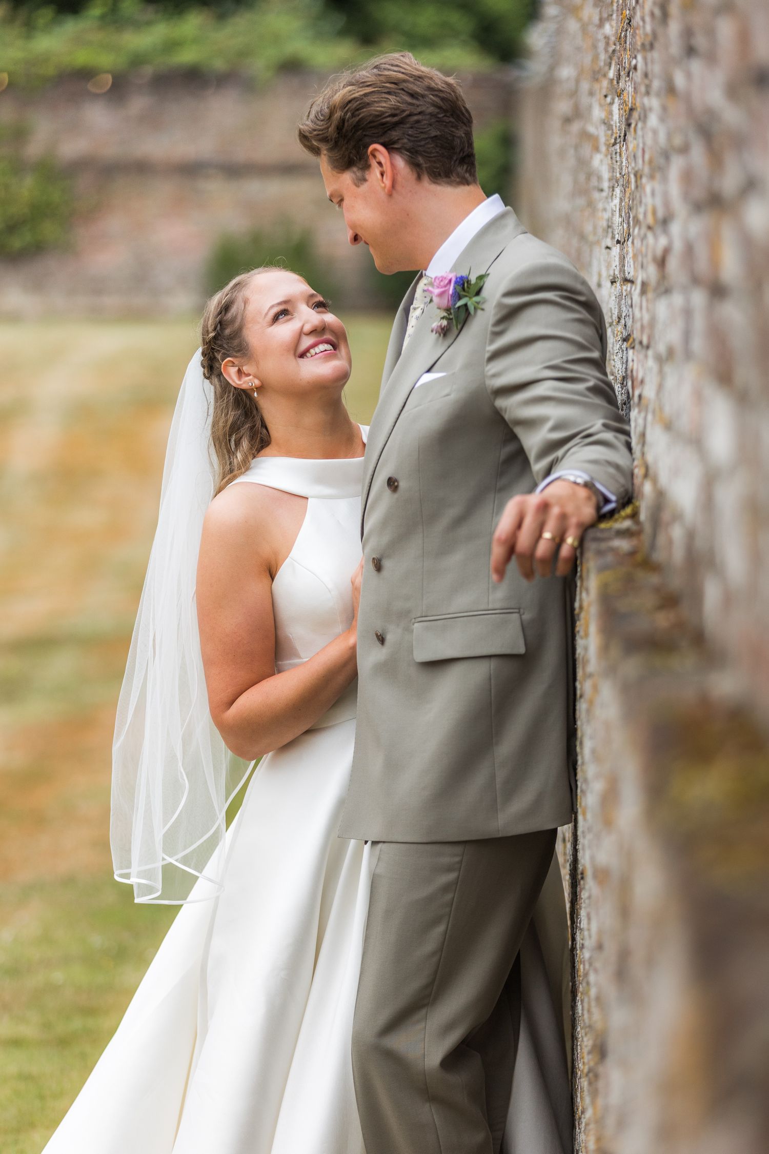 Romantic wedding moment captured against stone pillars outdoors.