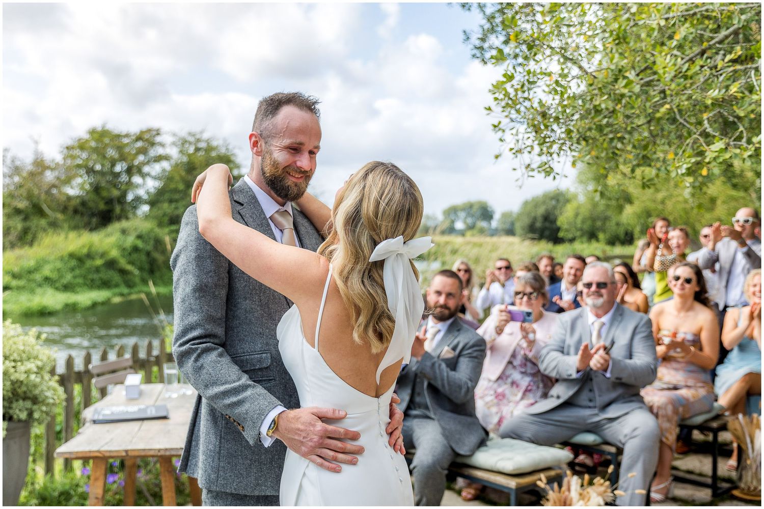 Joyful first dance moment at outdoor wedding with guests applauding.