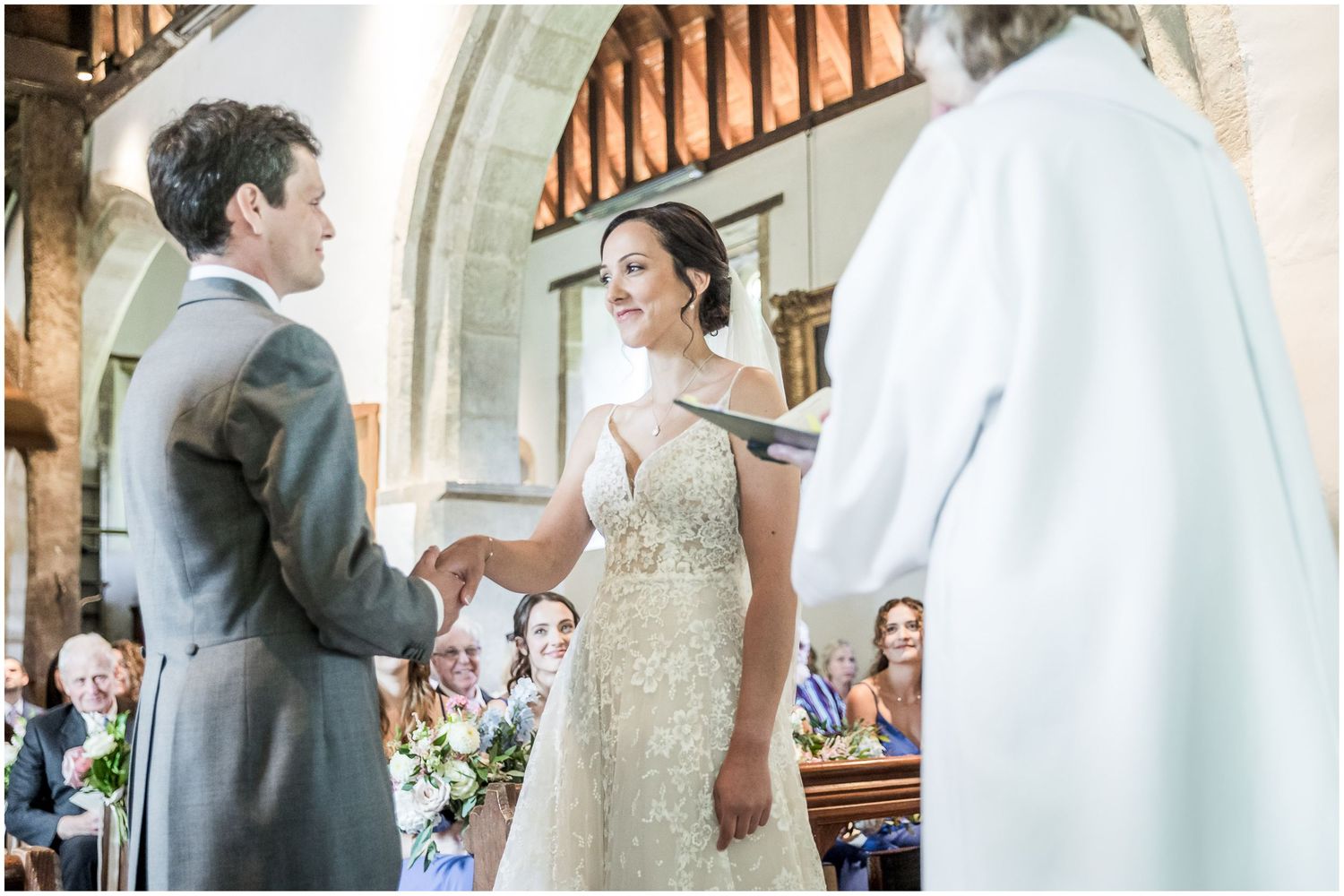 Wedding ceremony proceedings inside historic church with ornate wooden details.