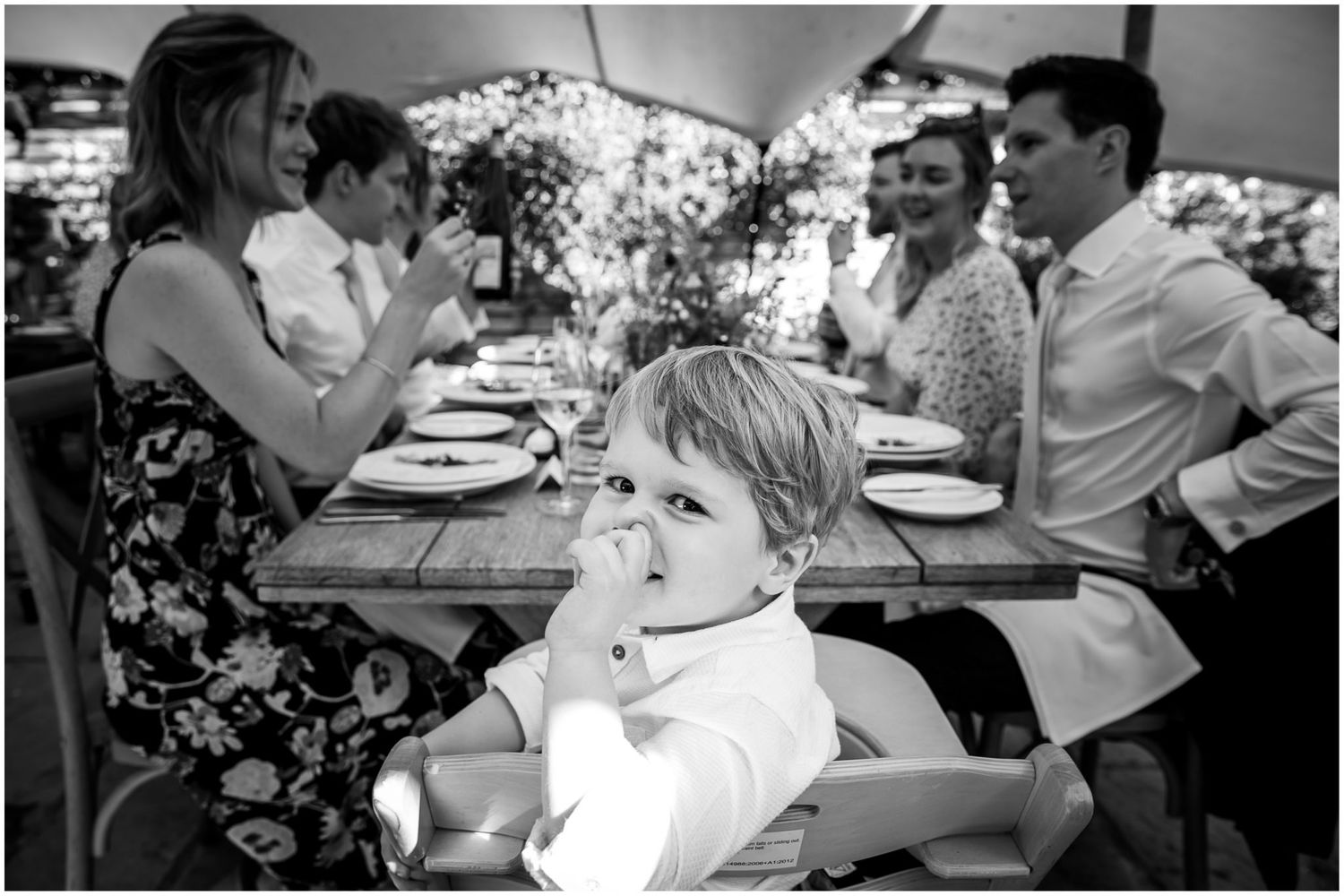 Monochrome images capturing candid moments of guests dining and socializing at a wedding reception.