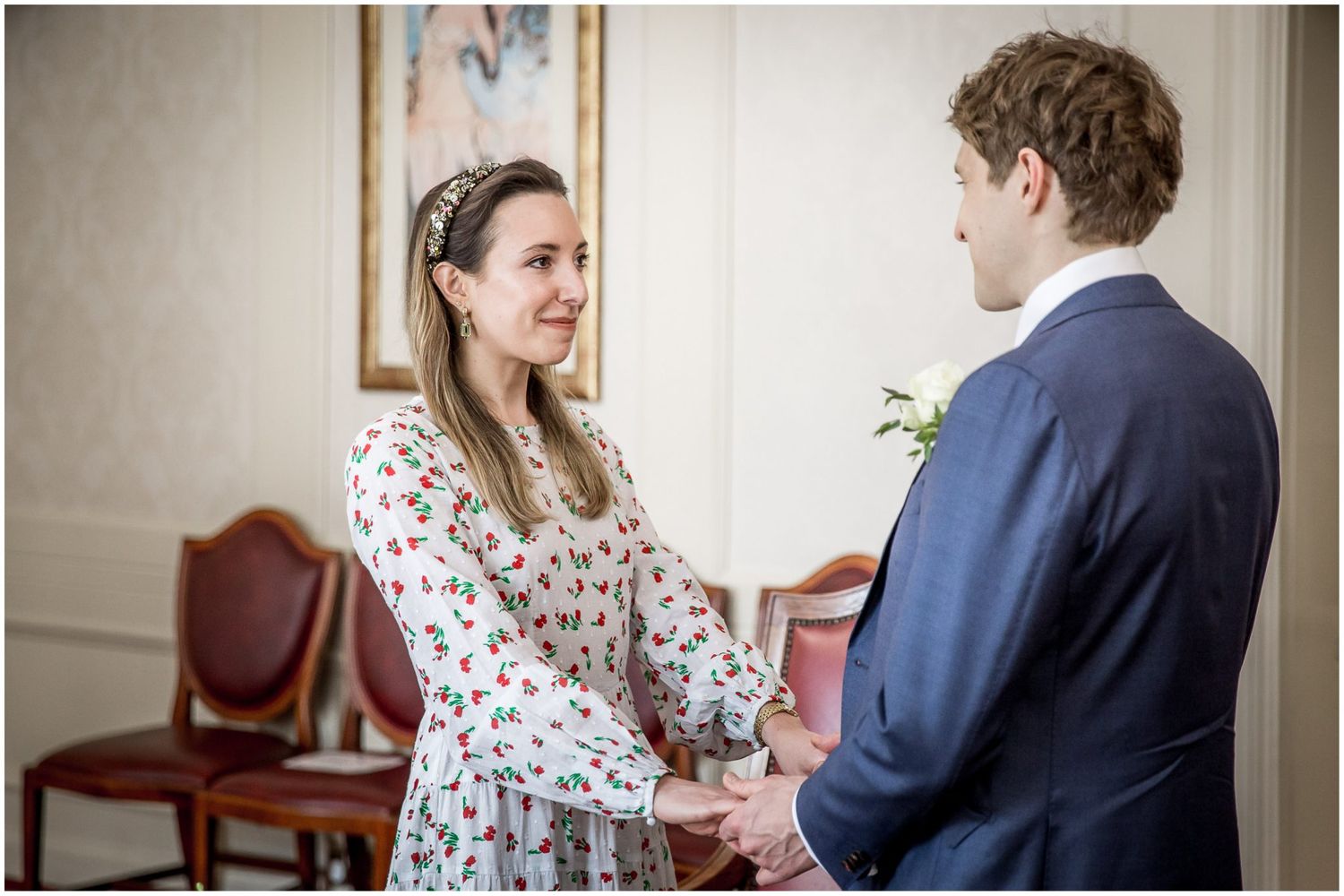 Intimate ceremony moment captured in an elegant indoor setting with floral dress details.
