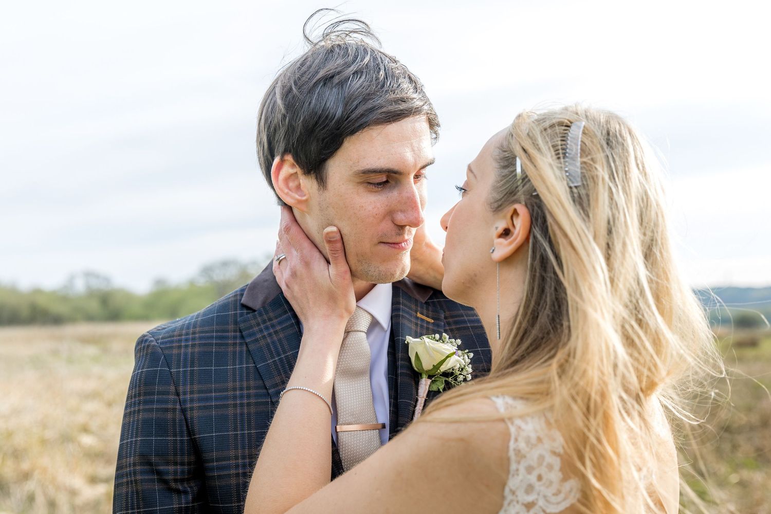 A romantic couple shares an intimate moment in a scenic outdoor setting with mountains in the background.