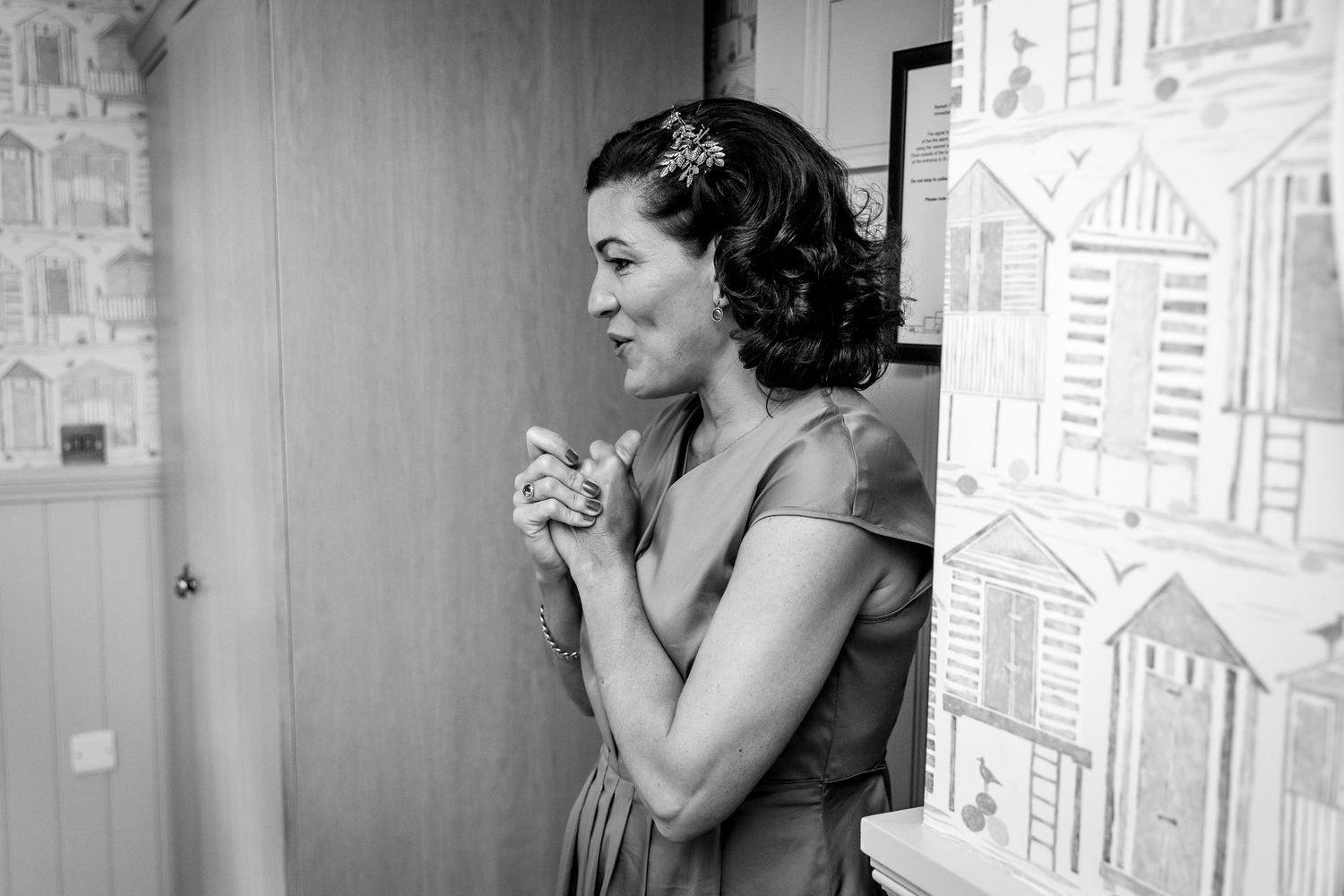 Black and white photo of wedding preparations in a room with patterned wallpaper.