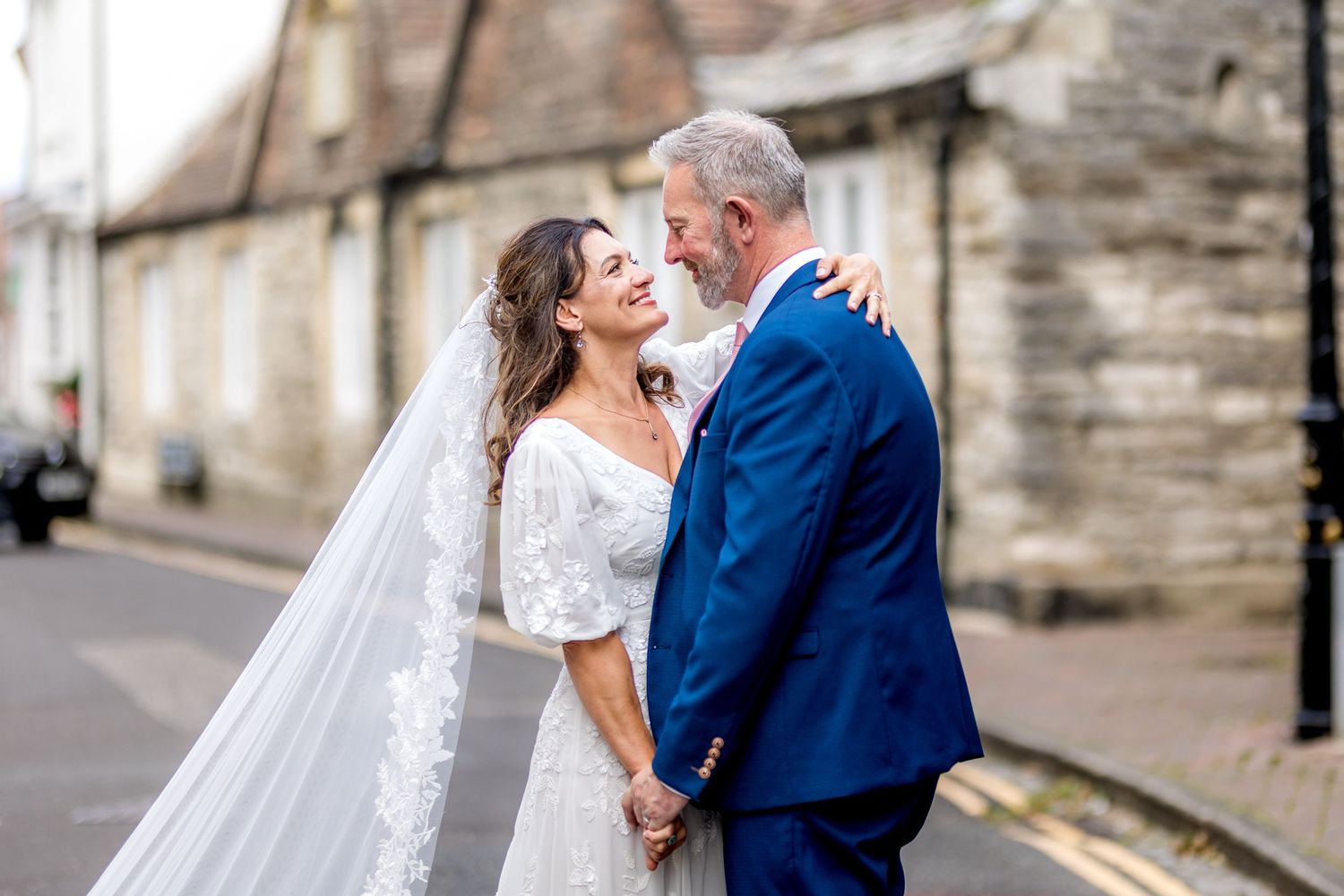 A romantic wedding portrait on a quiet village street with historic architecture.
