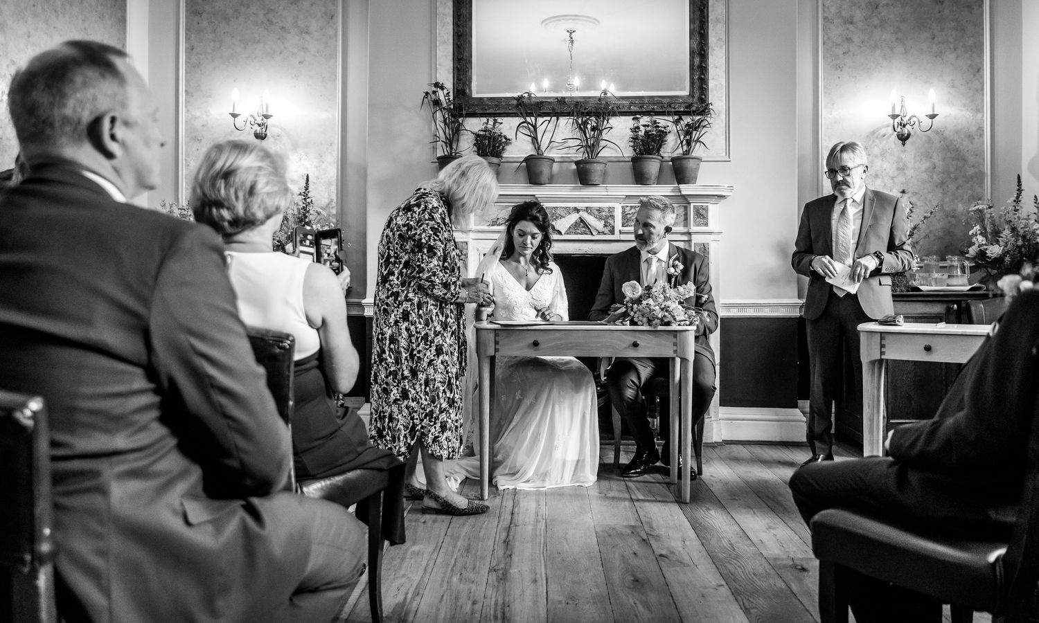 A black and white photo of a wedding ceremony in a traditional room with decorative details.