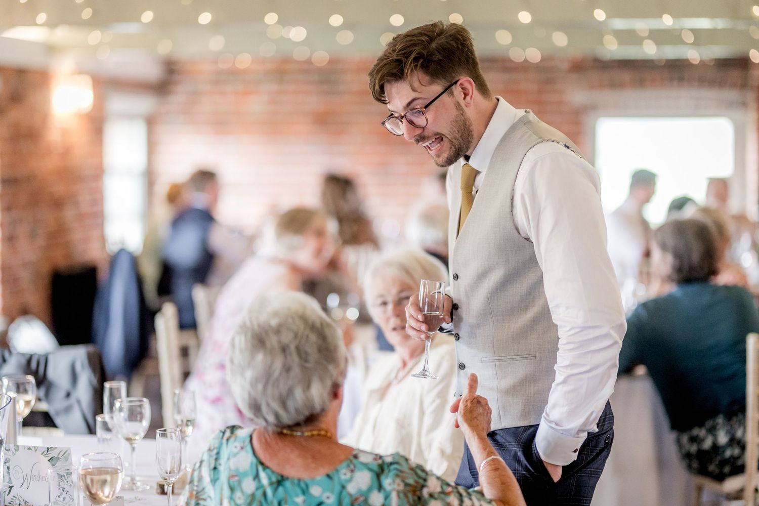 Casual reception moments with guests mingling in bright brick-walled venue.